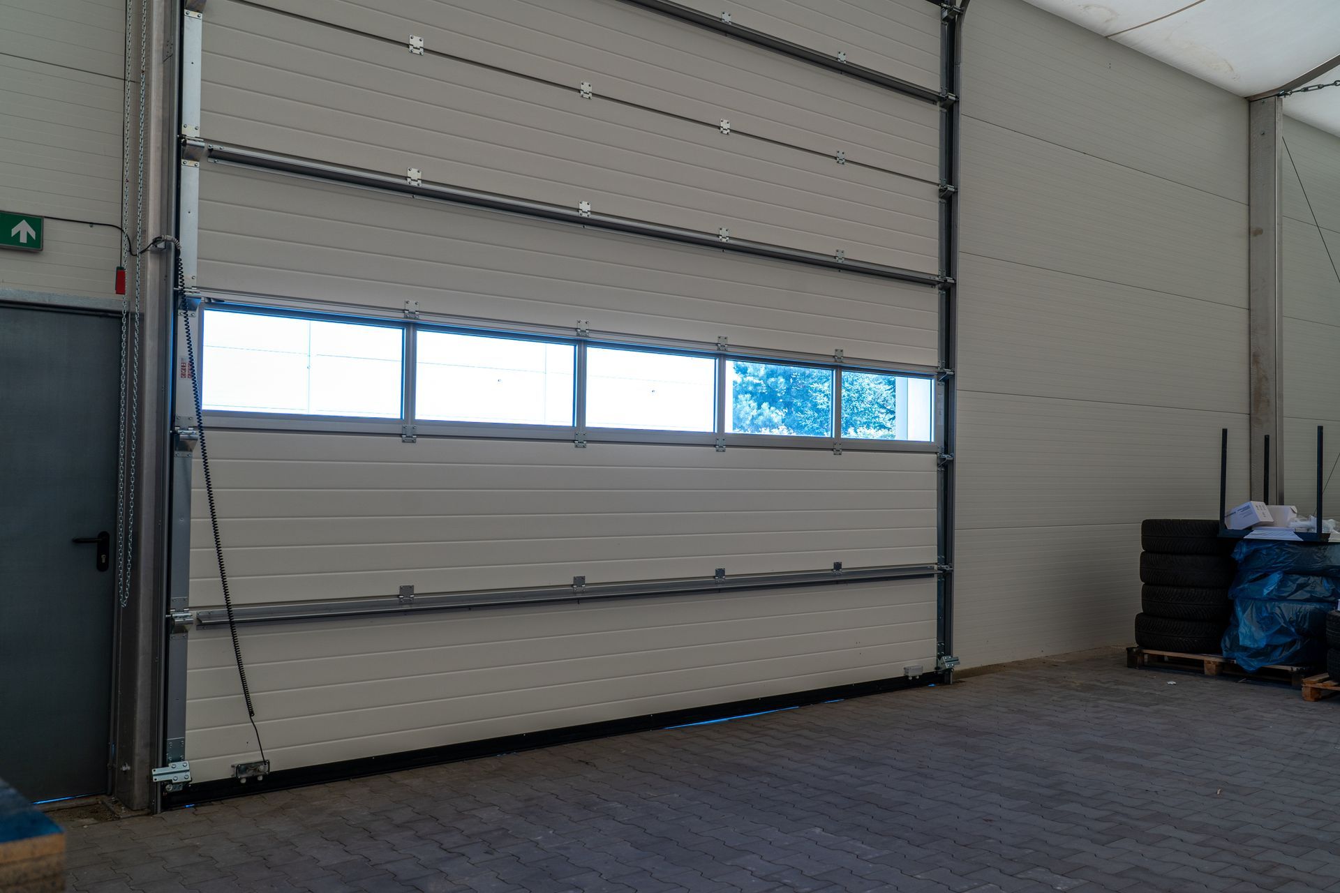 Residential door with wooden entryway and glass sidelights. Interior warehouse loading bay with large sectional door and window panels.