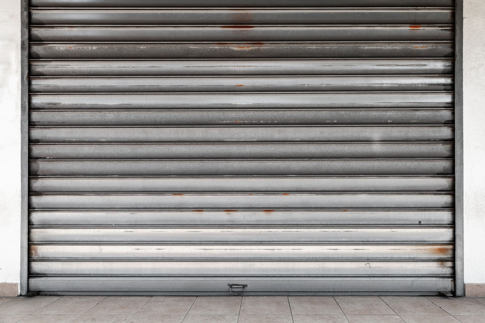 Closed, metallic, roll-up security shutter, likely on a storefront.