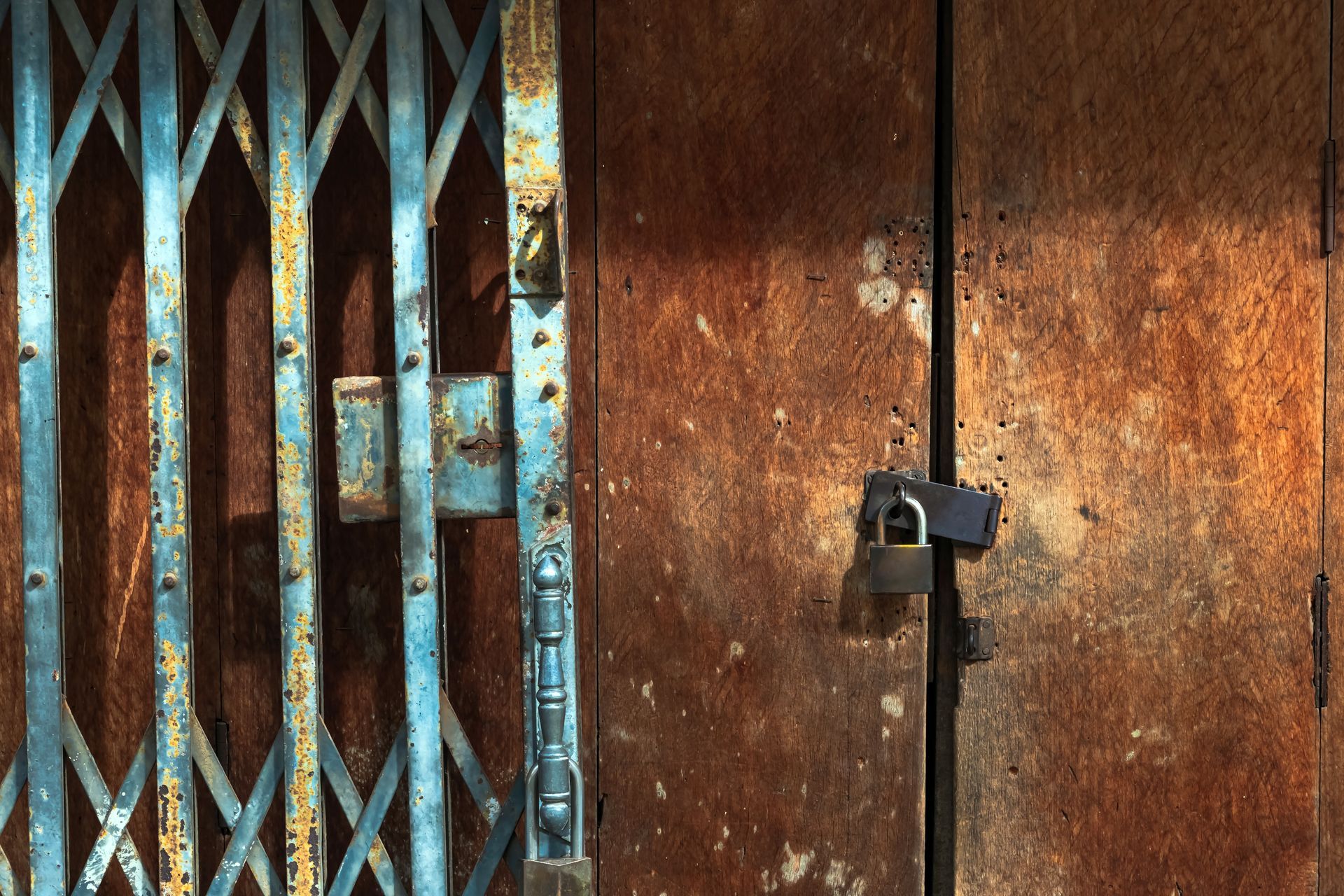 Old gold steel lock and damaged and rusted steel door on wooden door