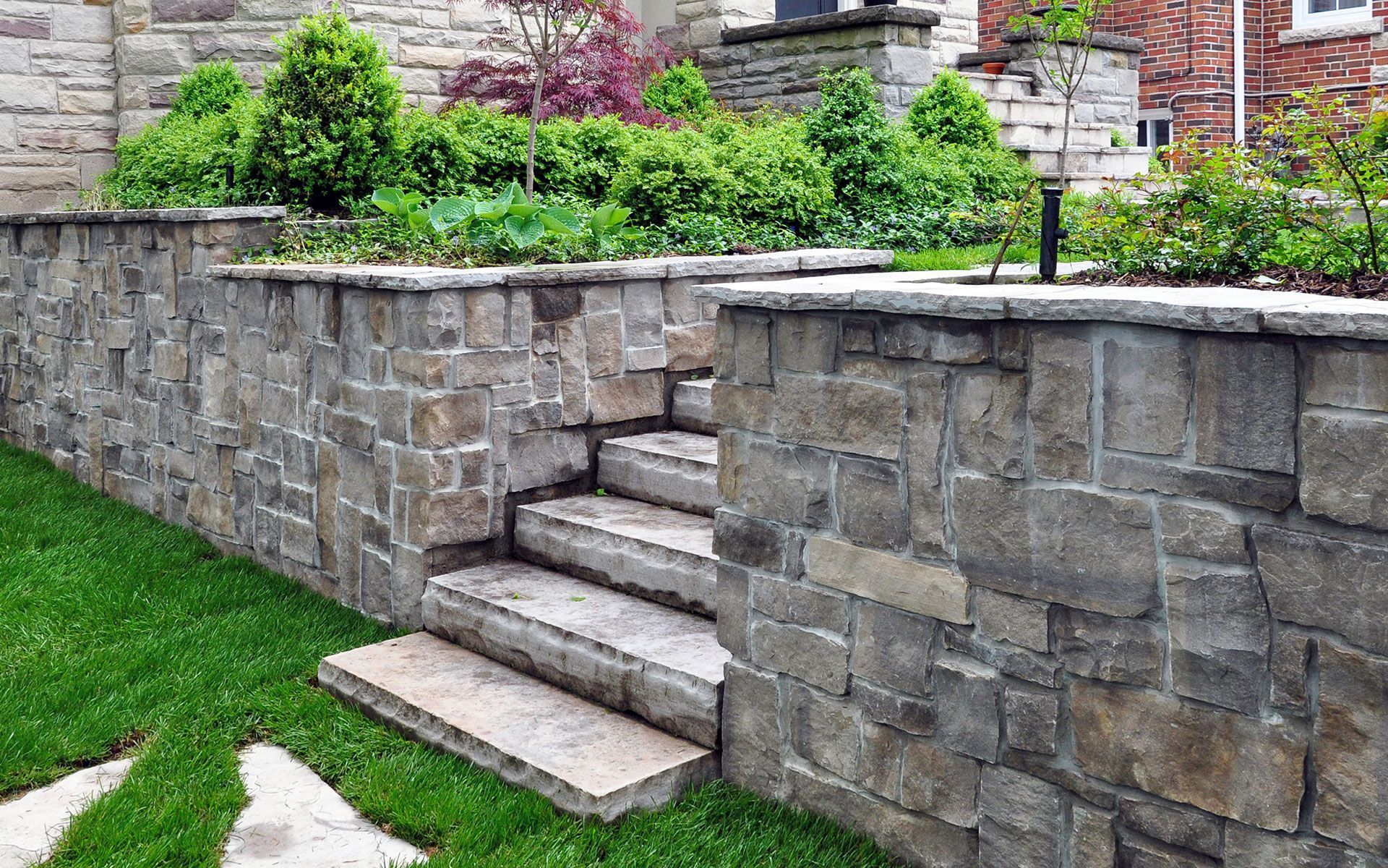A stone wall with stairs leading up to a house.