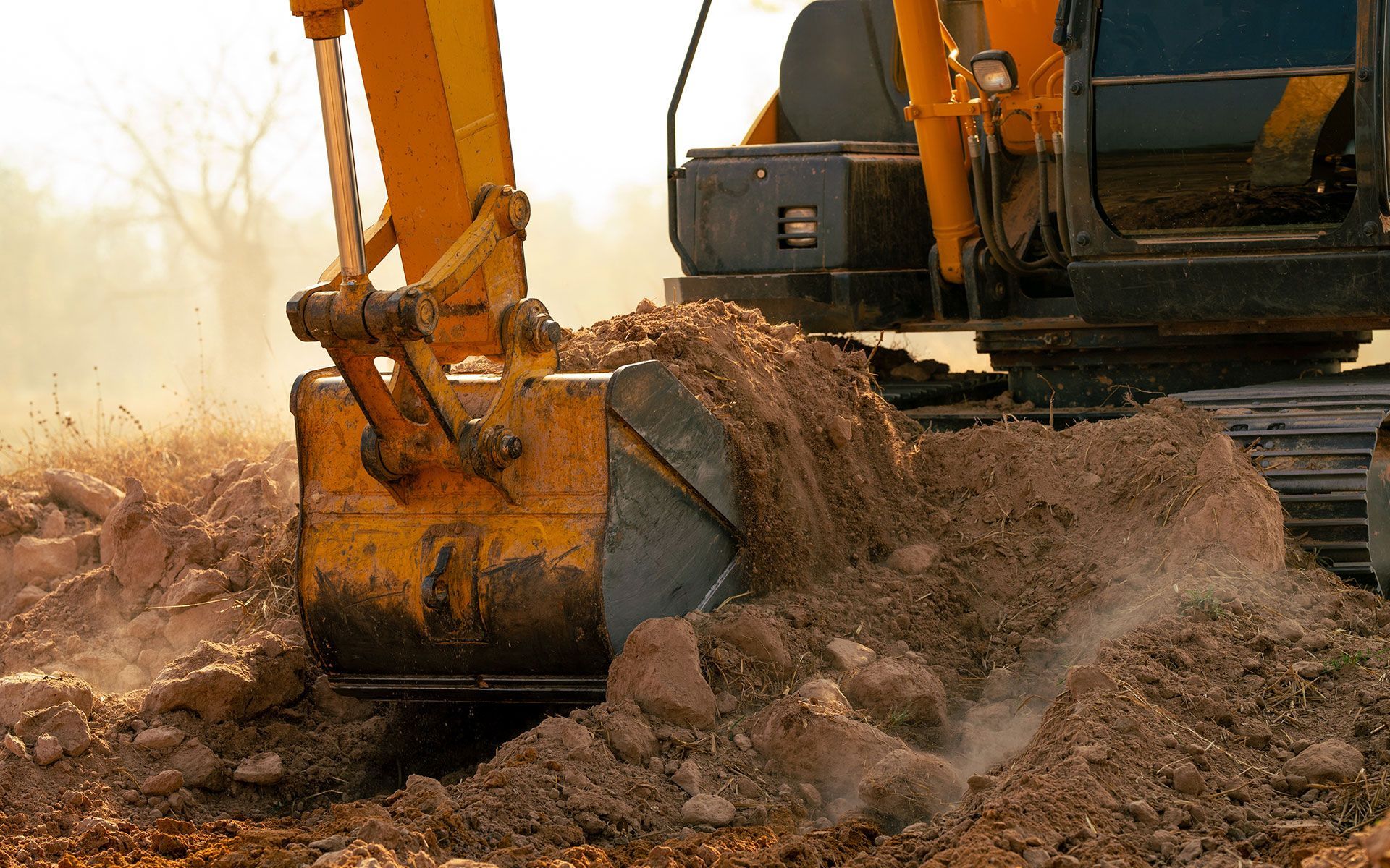 A yellow excavator is digging a hole in the dirt.