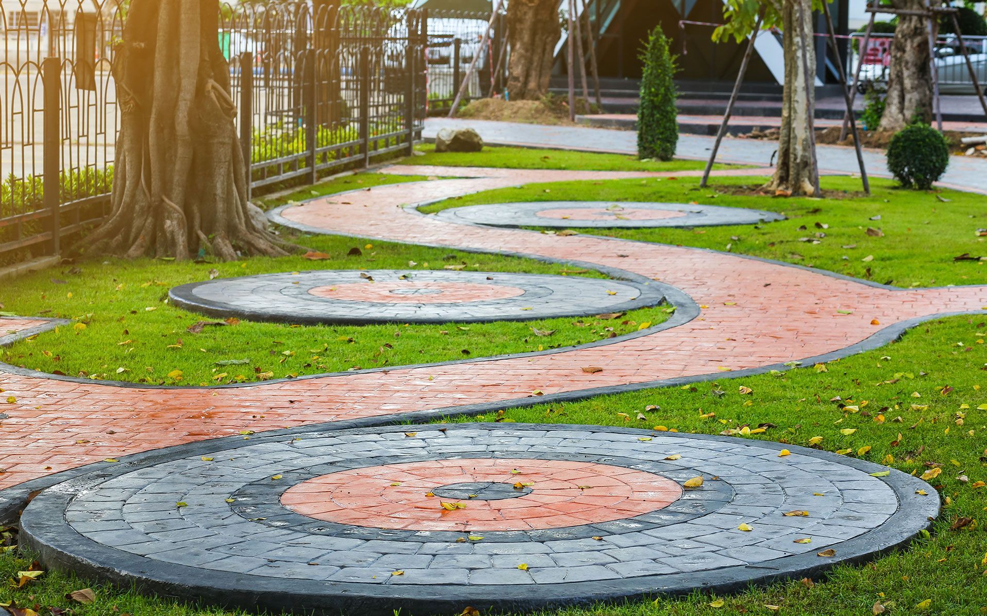 A brick walkway in a park with a circular design on it.