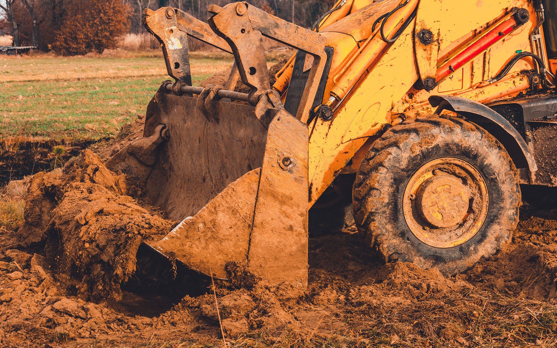 A bulldozer is digging a hole in the dirt in a field.