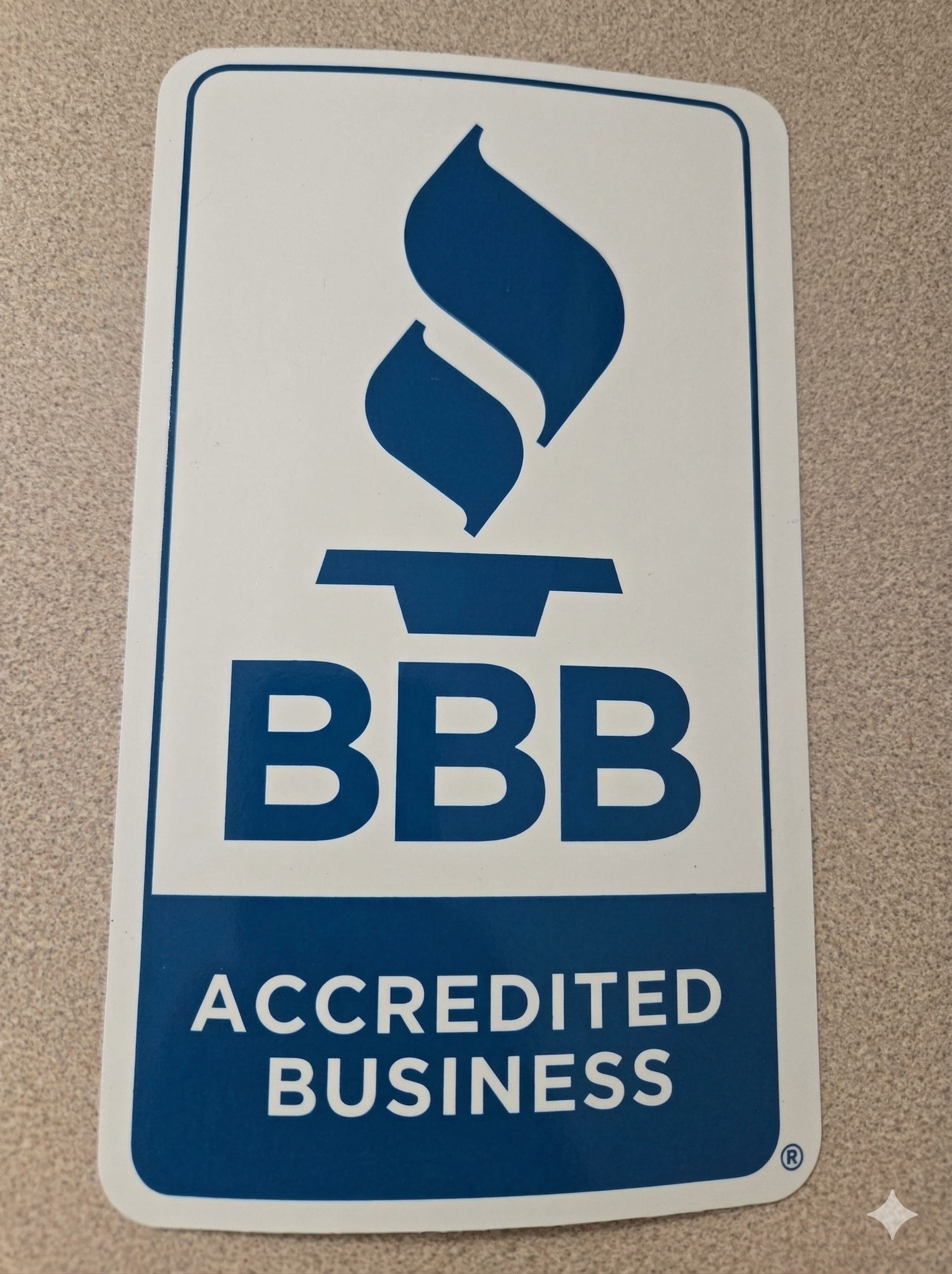 A blue and white Better Business Bureau (BBB) Accredited Business decal featuring a stylized torch icon.