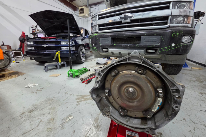 Auto repair shop with two trucks and a removed transmission in the foreground | DFW Auto Repair