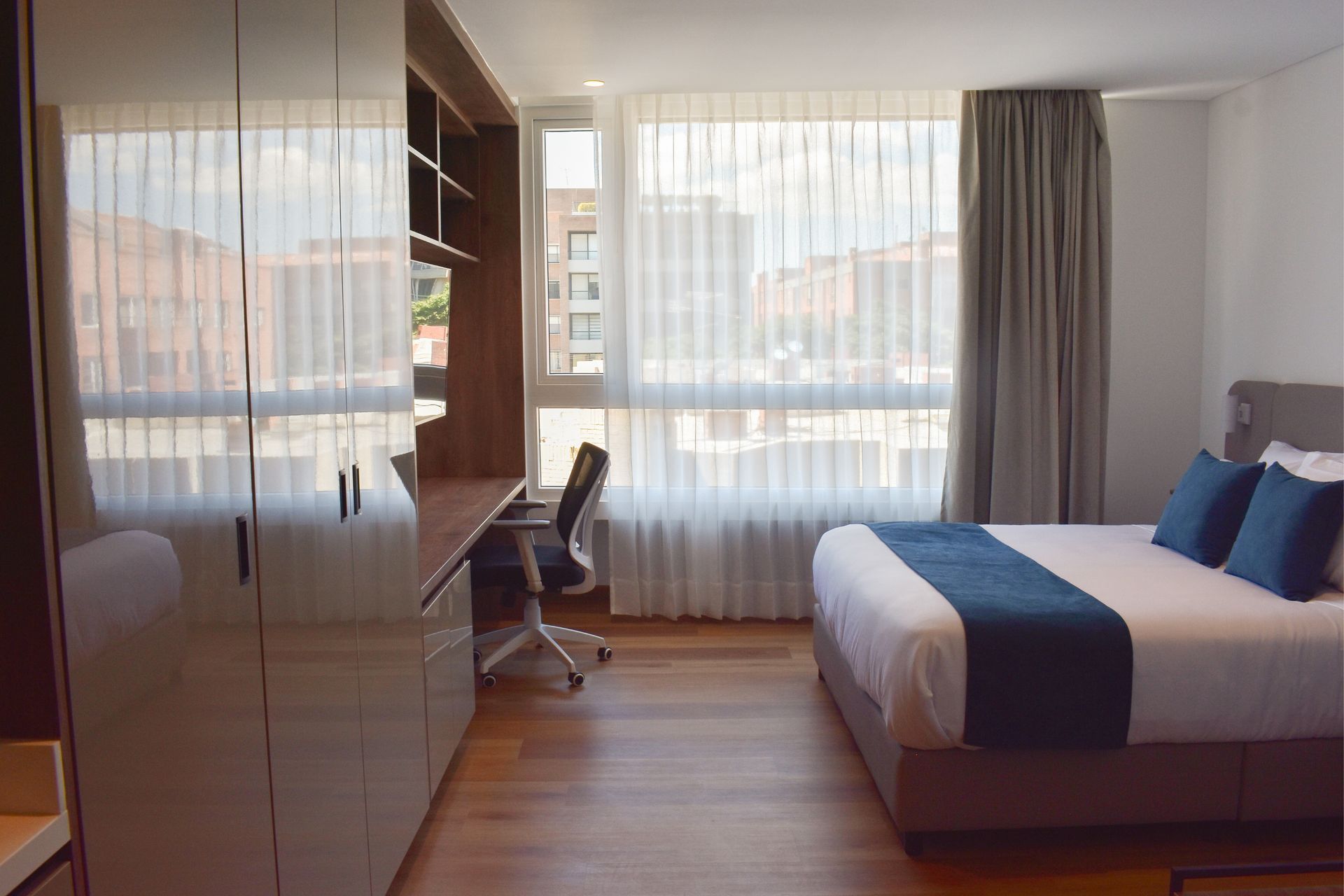 Habitación de VOU Suite con cama amplia y un escritorio para trabajar durante un viaje de negocios en bogota