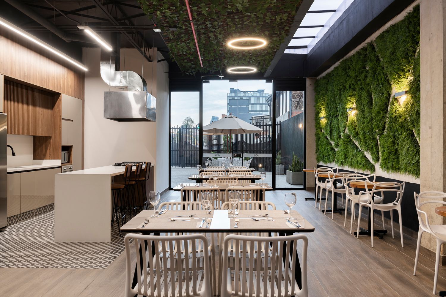 Comedor moderno con mesas de madera y jardín en las instalaciones de hospedaje en bogota de VOU.