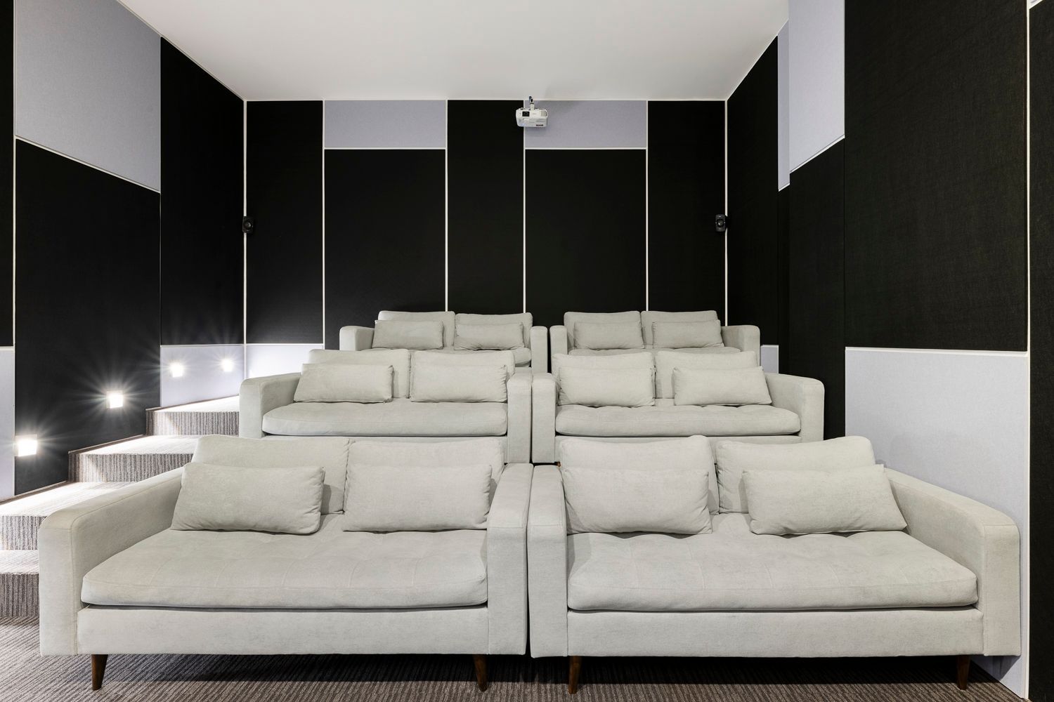 Sala de cine privada con sillones blancos y cómodos en VOU suites, ideal para quienes buscan apartahotel bogota