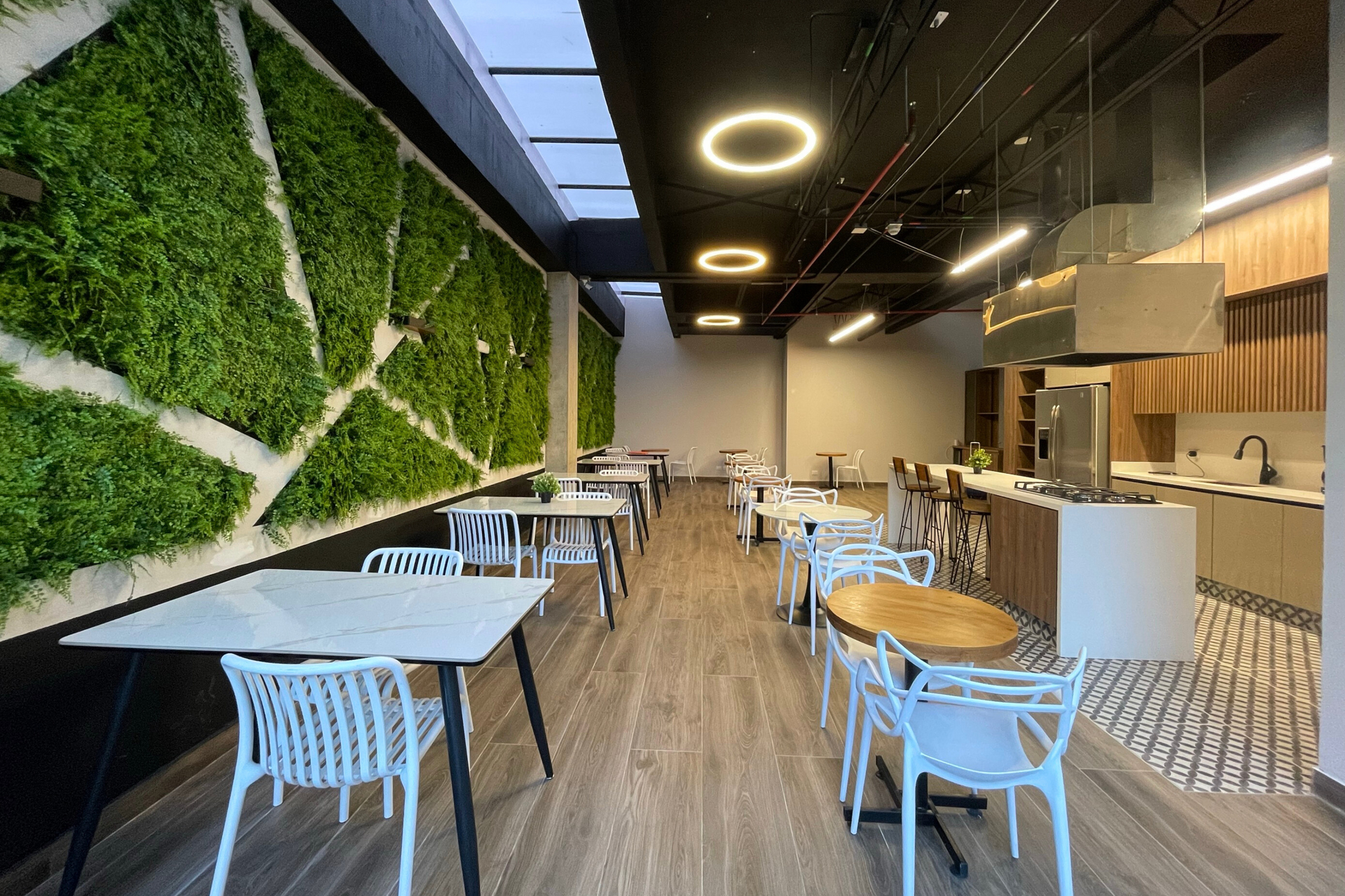 Cafetería con mesas blancas y un extenso muro verde en un hotel en bogota para viaje de negocios