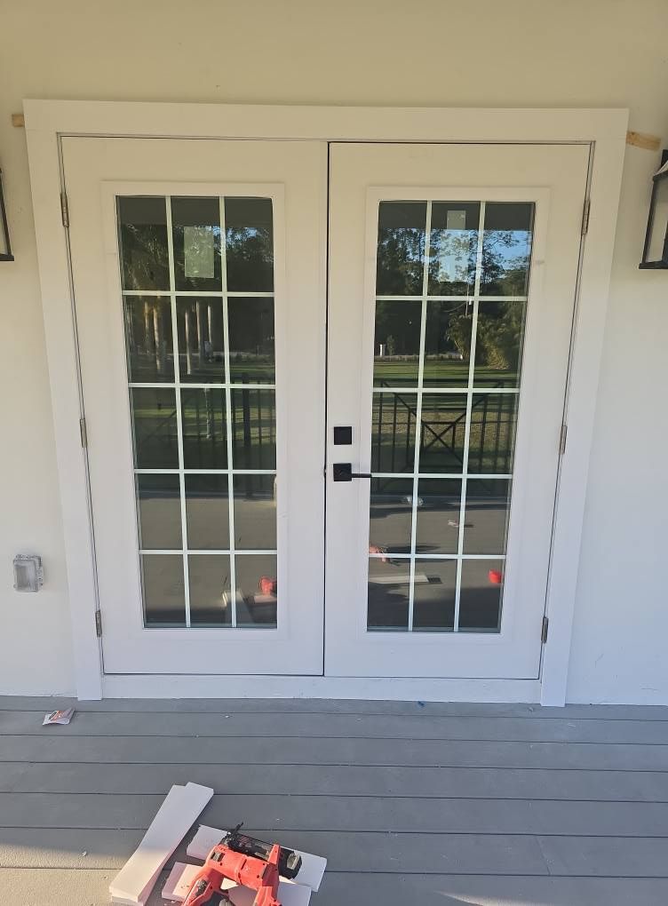 White French doors with multiple glass panes and a black handle. Exterior setting.