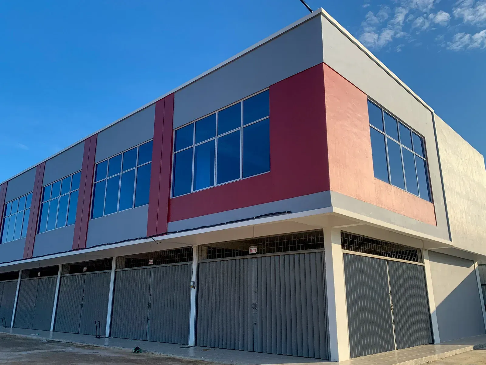 Corner of a modern commercial building with red and beige walls and large blue-tinted windows