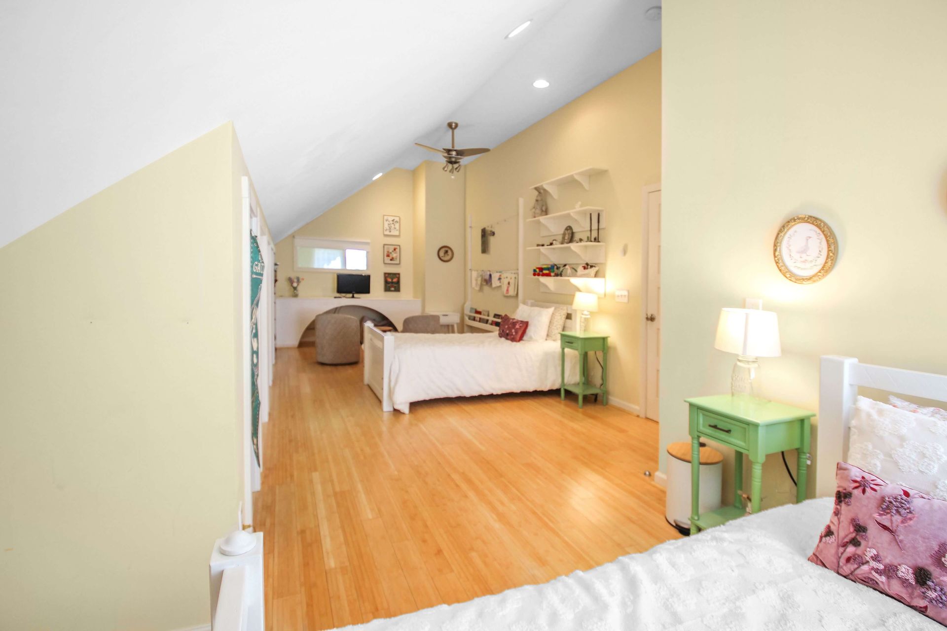 Bedroom with light yellow walls, hardwood floors, and a bed with white linens.