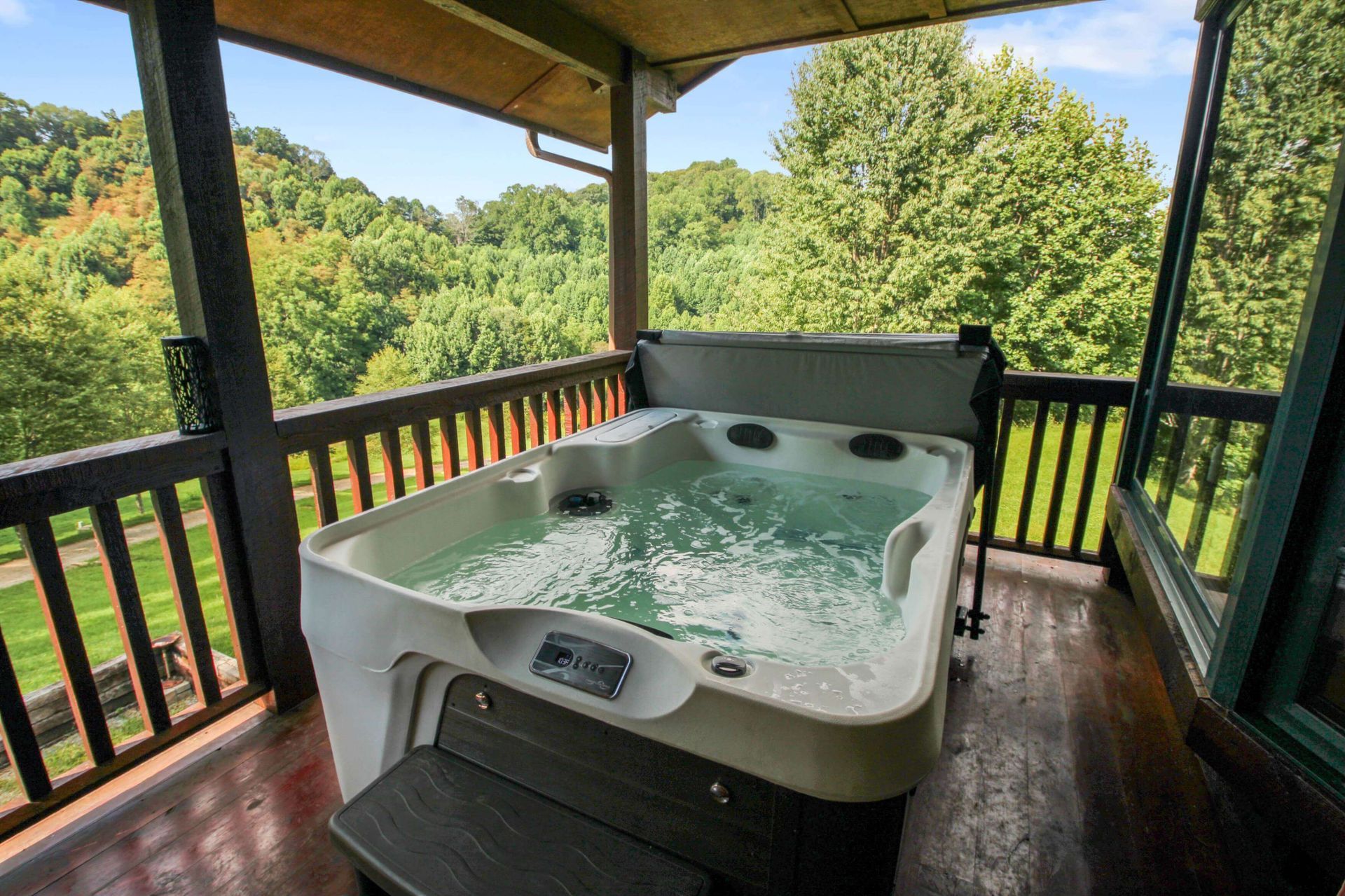 Hot tub on a wooden deck, overlooking a lush green valley.