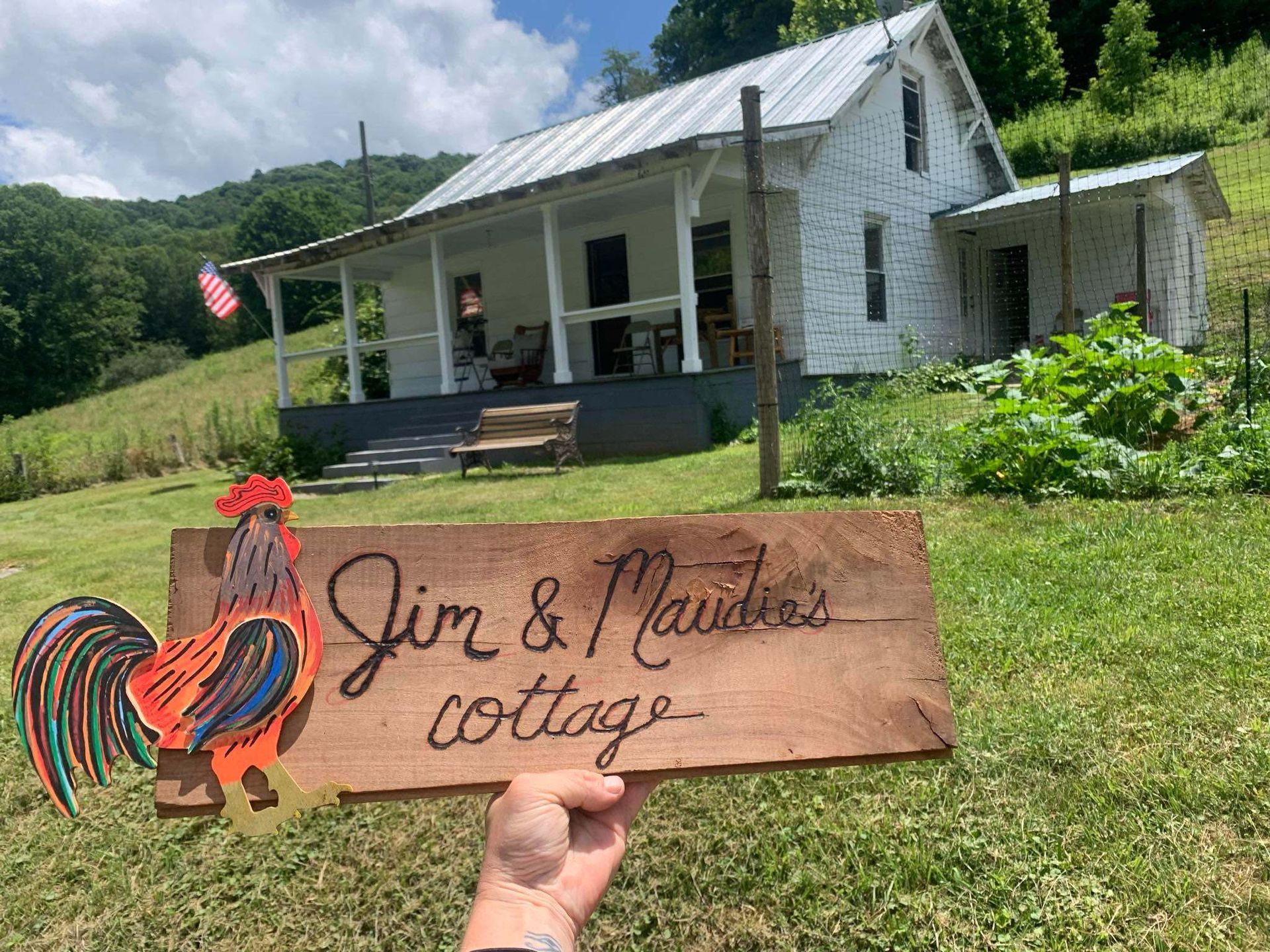 Cottage with porch and garden, sign reading