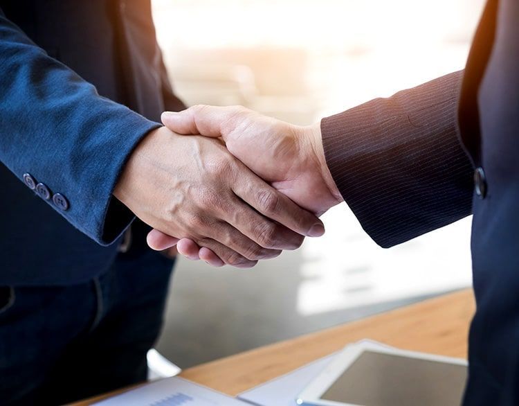 Dos hombres de negocios se dan la mano sobre una mesa.