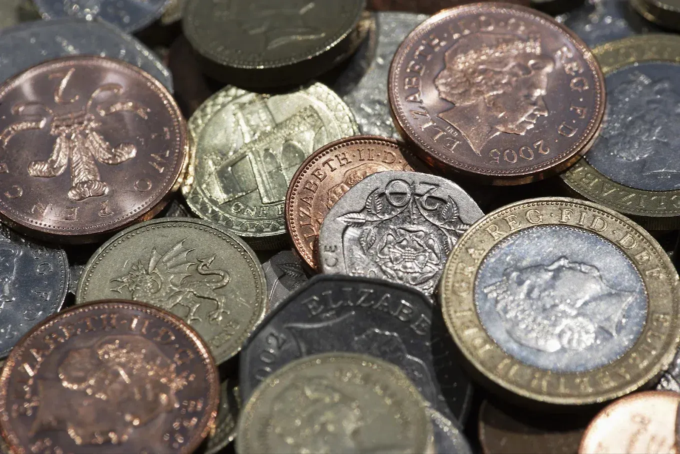 Stacks of gold, silver, and copper coins arranged in rows on a soft blurred background