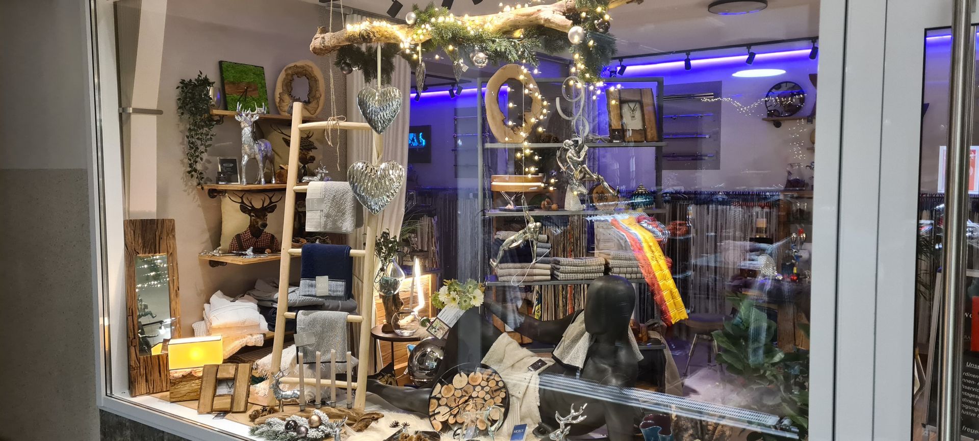 Eine weihnachtliche Schaufensterdekoration in einem Geschäft mit einer Leiter und einem Weihnachtsbaum.