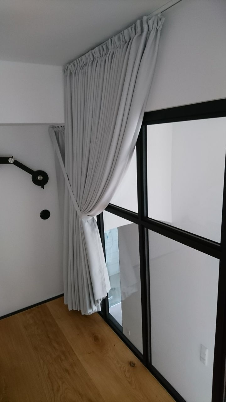 Ein weißer Vorhang hängt aus einem Fenster in einem Zimmer.