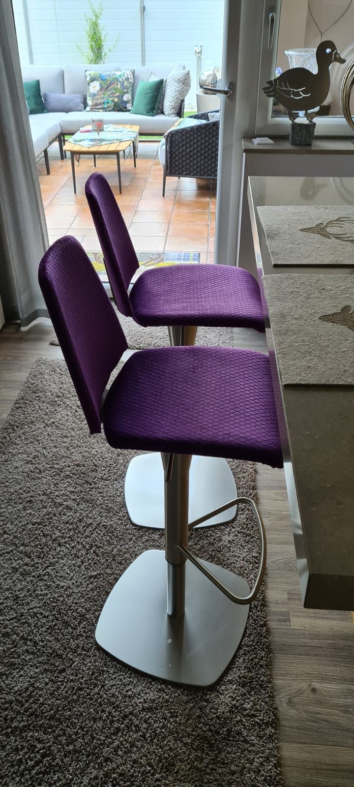 Zwei lila Barhocker stehen auf einem Teppich in einem Wohnzimmer.