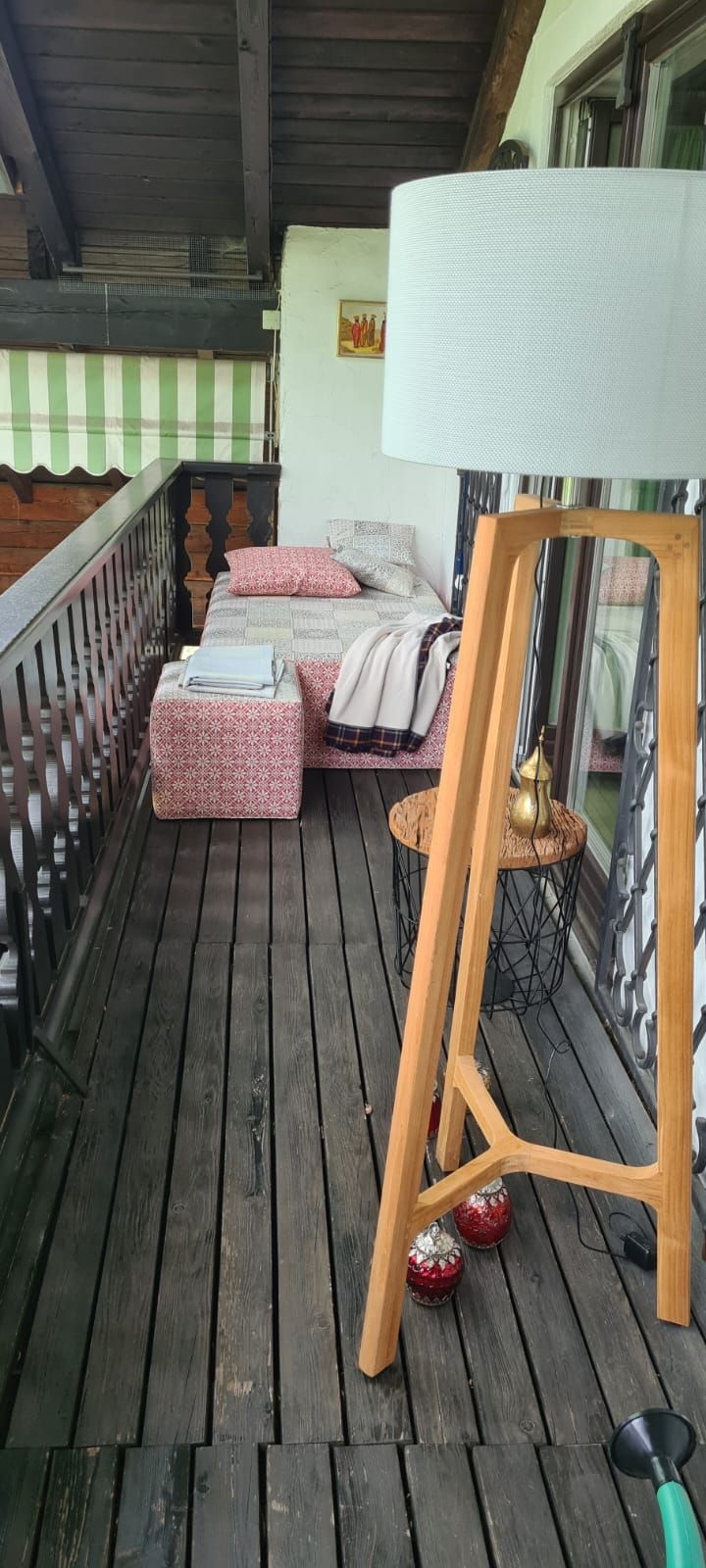 Auf einem Holztisch auf einem Balkon steht eine Lampe.