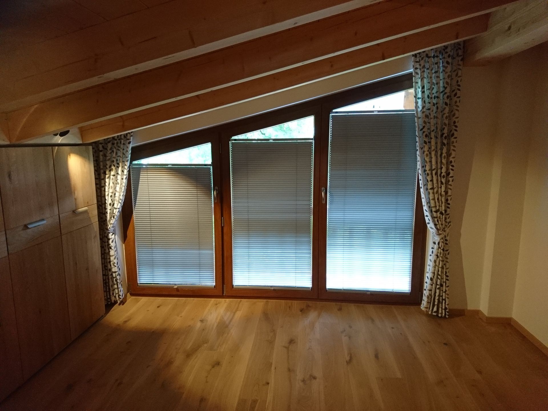 Ein leerer Raum mit Holzboden und einem großen Fenster