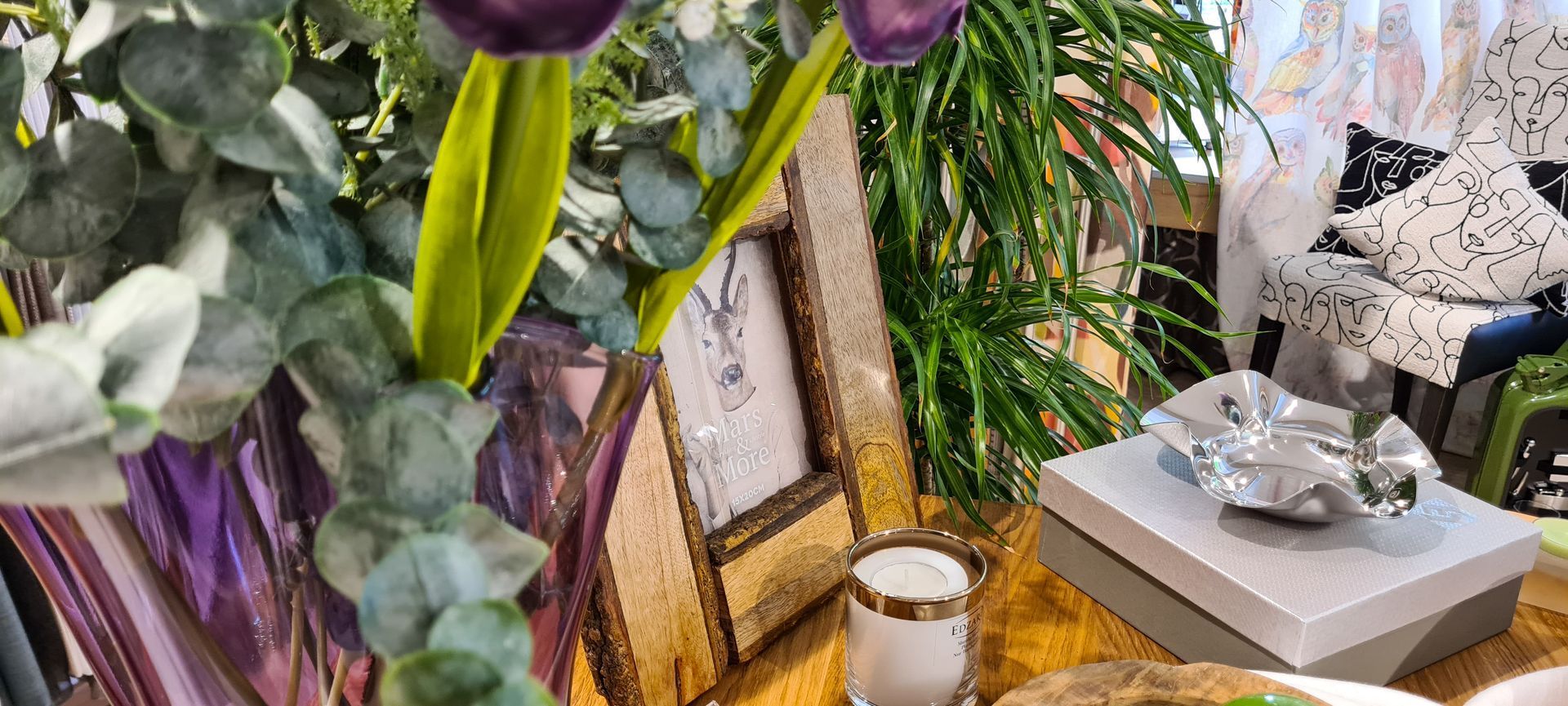 Auf einem Tisch steht eine Vase mit Blumen neben einem Bilderrahmen.