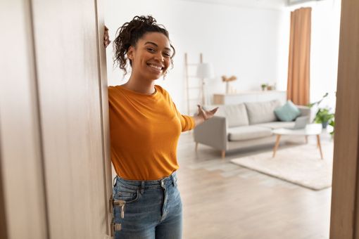 Stock photo of a woman inviting the viewer into her home