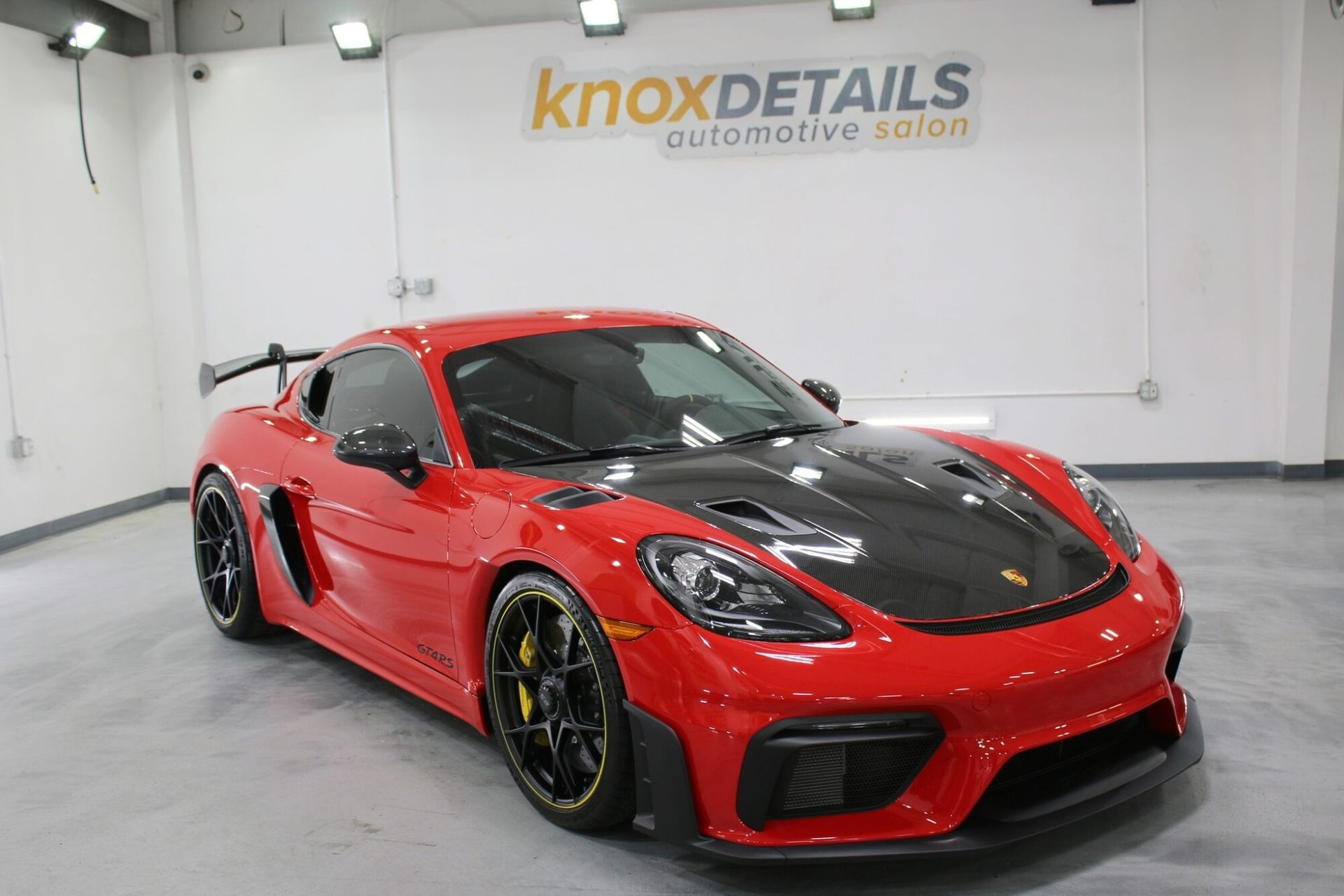 Red Porsche sports car with black hood in a showroom