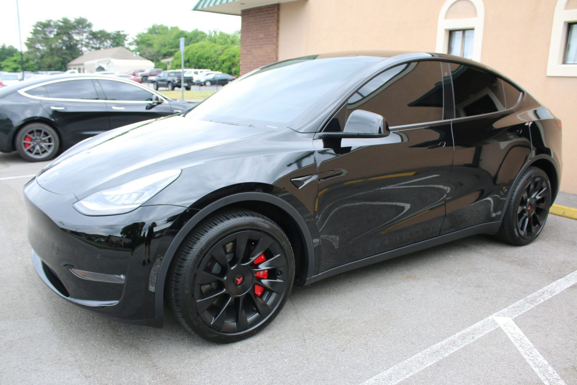 Black Tesla Model Y parked outside a building, with dark tinted windows and black rims