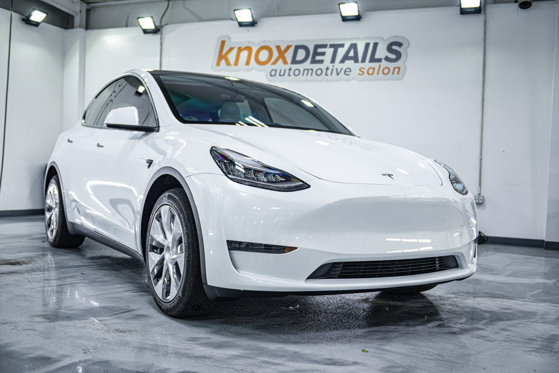 White Tesla sedan in a showroom with Knox Details branding on the wall