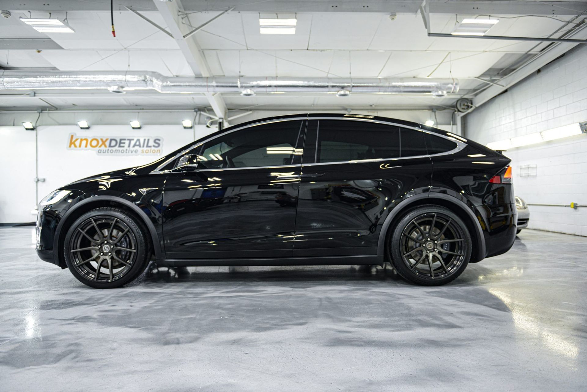 Black compact SUV in a bright auto detailing shop, side view on a polished floor.