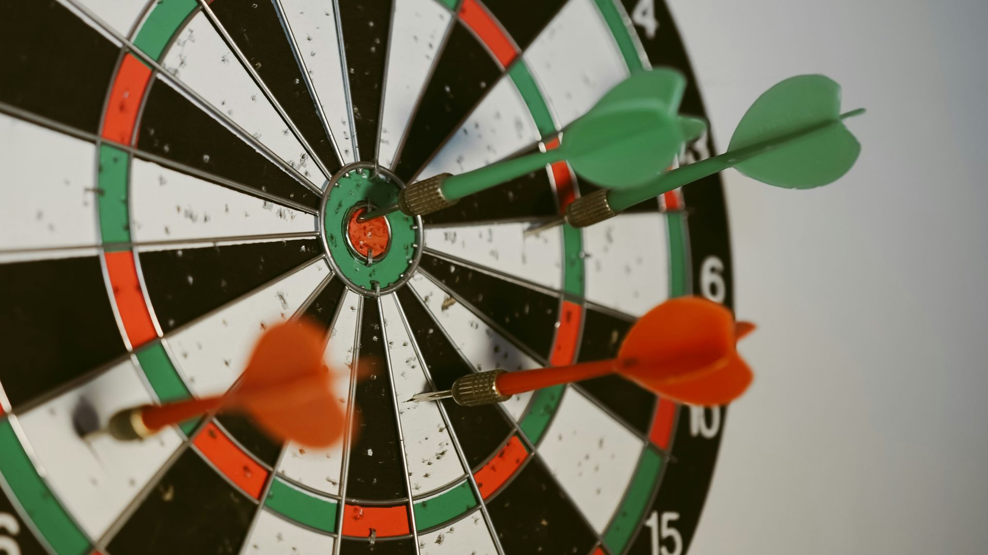 Dart board with 2 green darts and 2 red darts