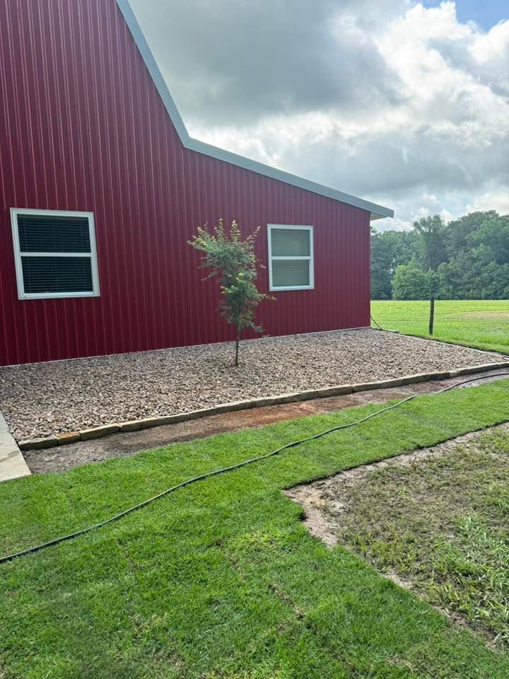 Red building with gravel bed, small tree, and green lawn.