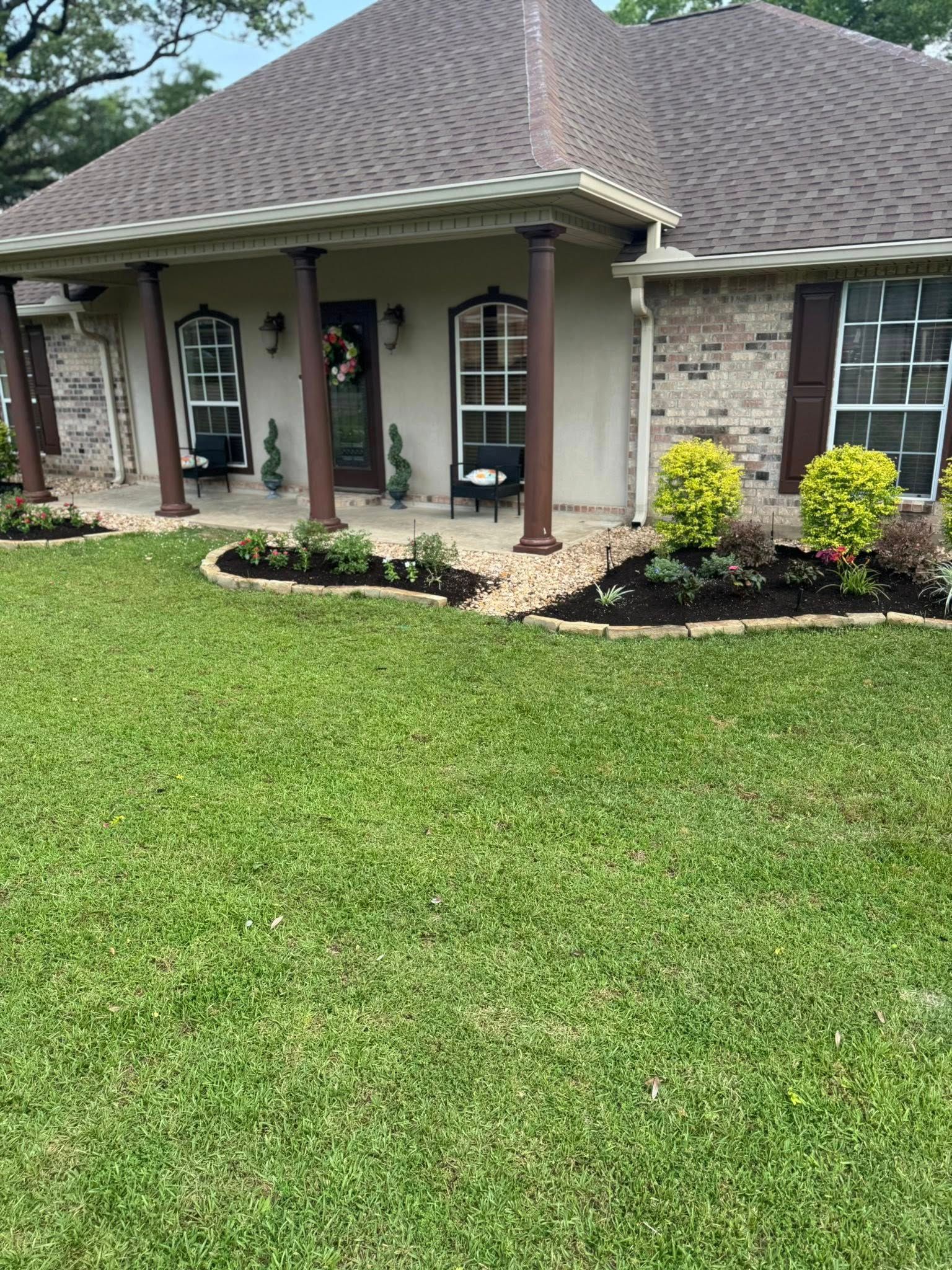 Tan house with brown roof and landscaping; green lawn in front.