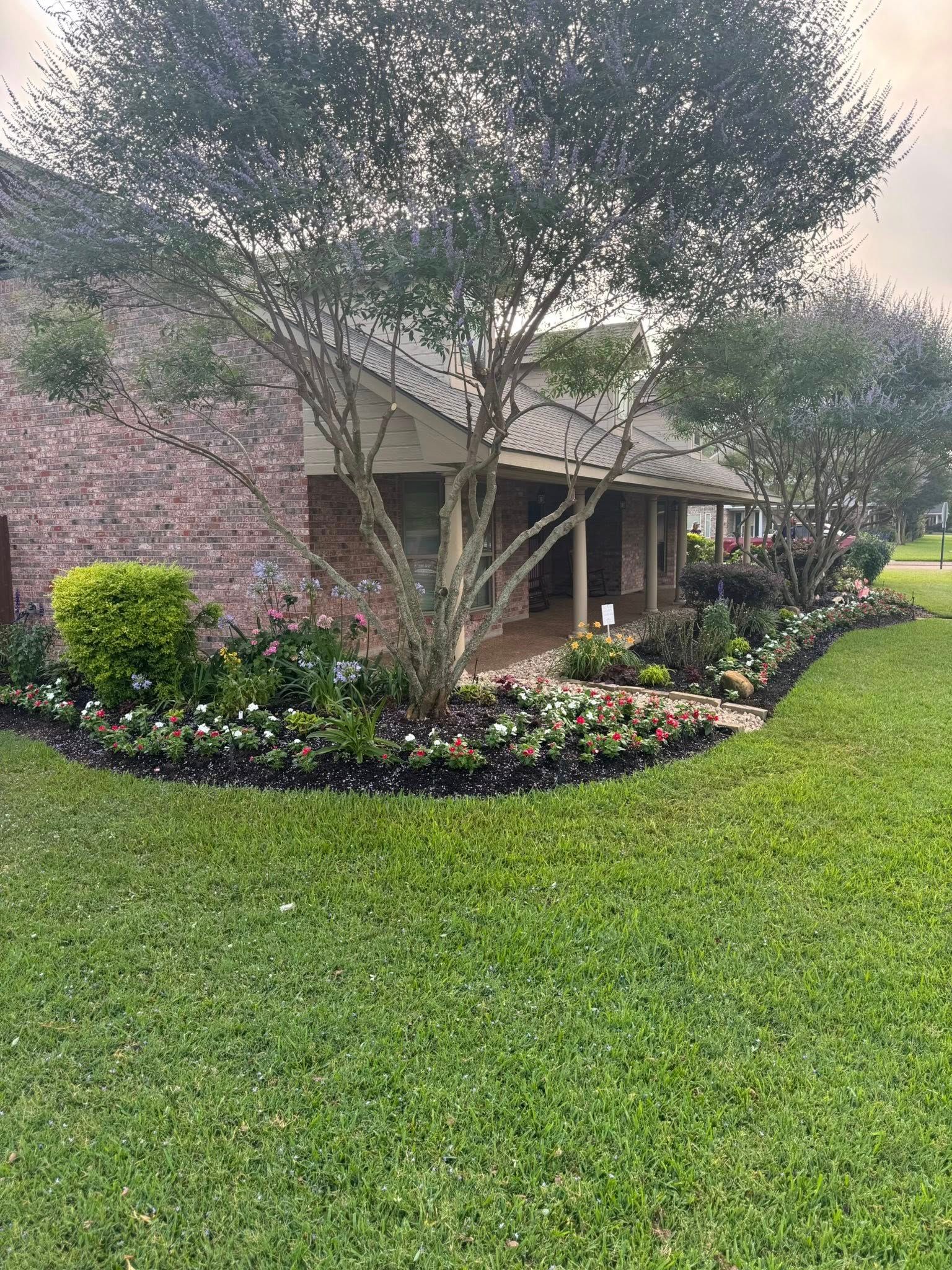 House exterior with lush landscaping, including flowers and shrubs, and a well-manicured lawn.