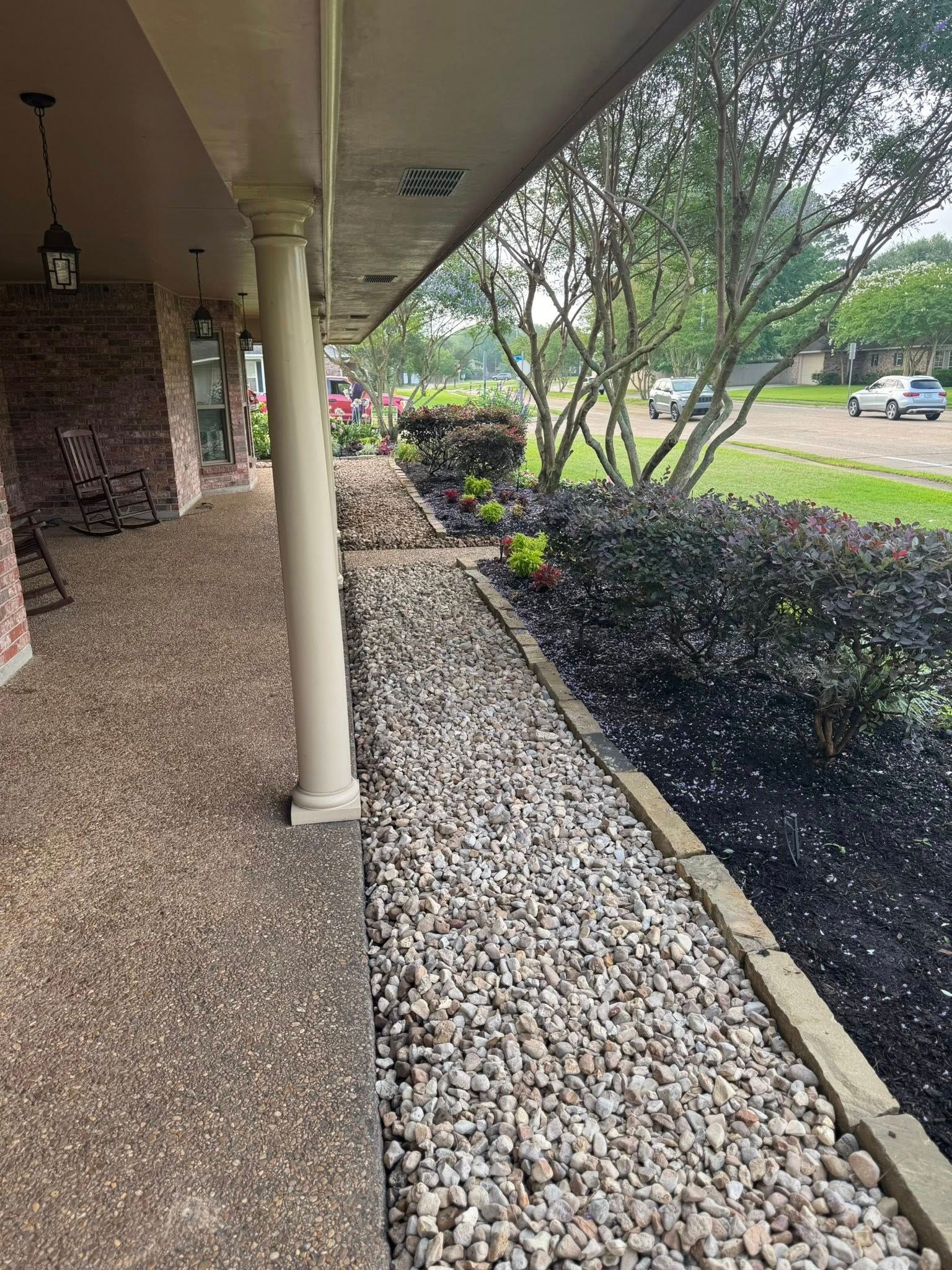 Exterior of a building with a pebbled walkway, garden, and bushes.