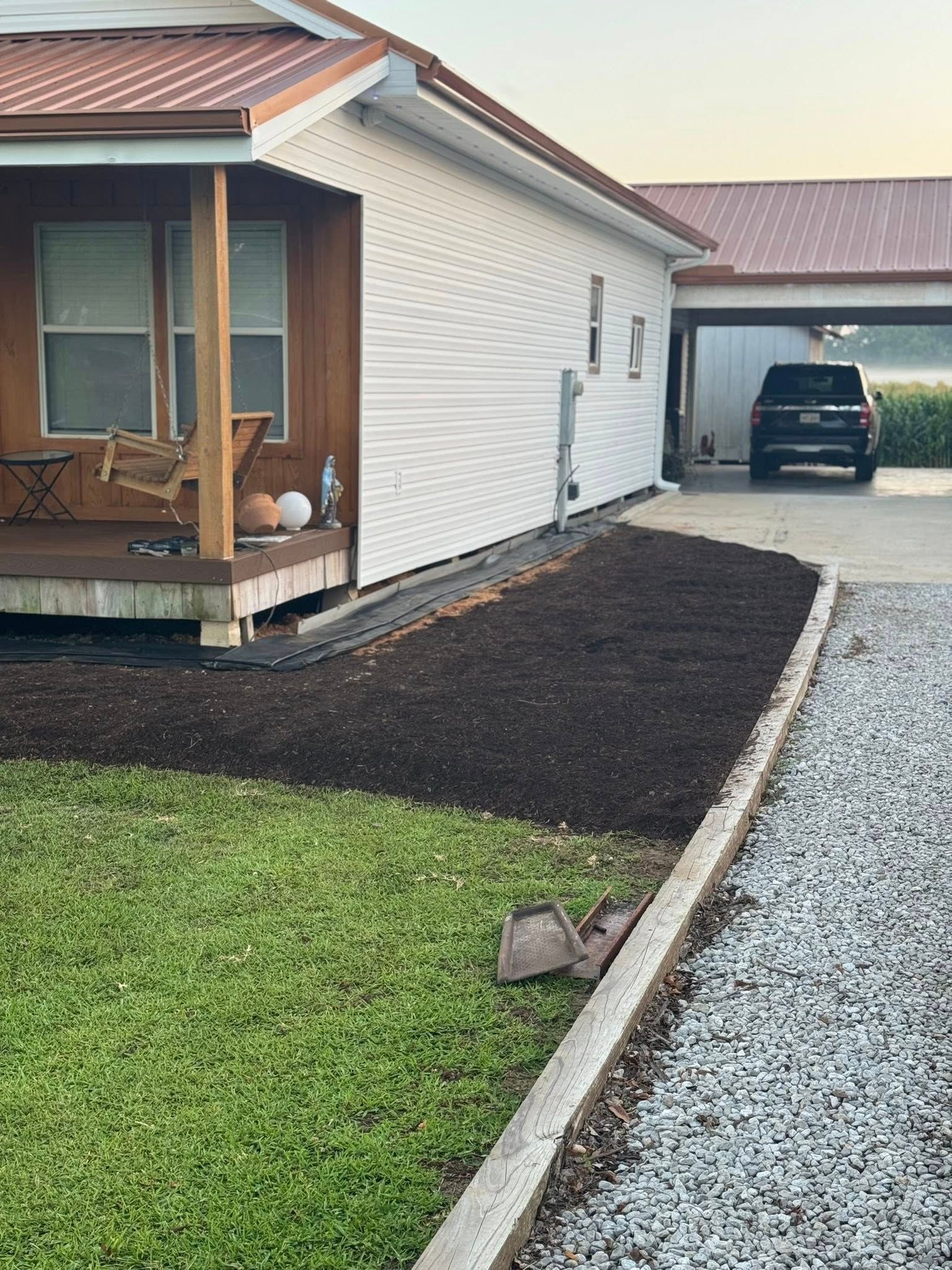 House exterior with carport. A dark SUV parked in the carport. Fresh mulch in the flower bed.