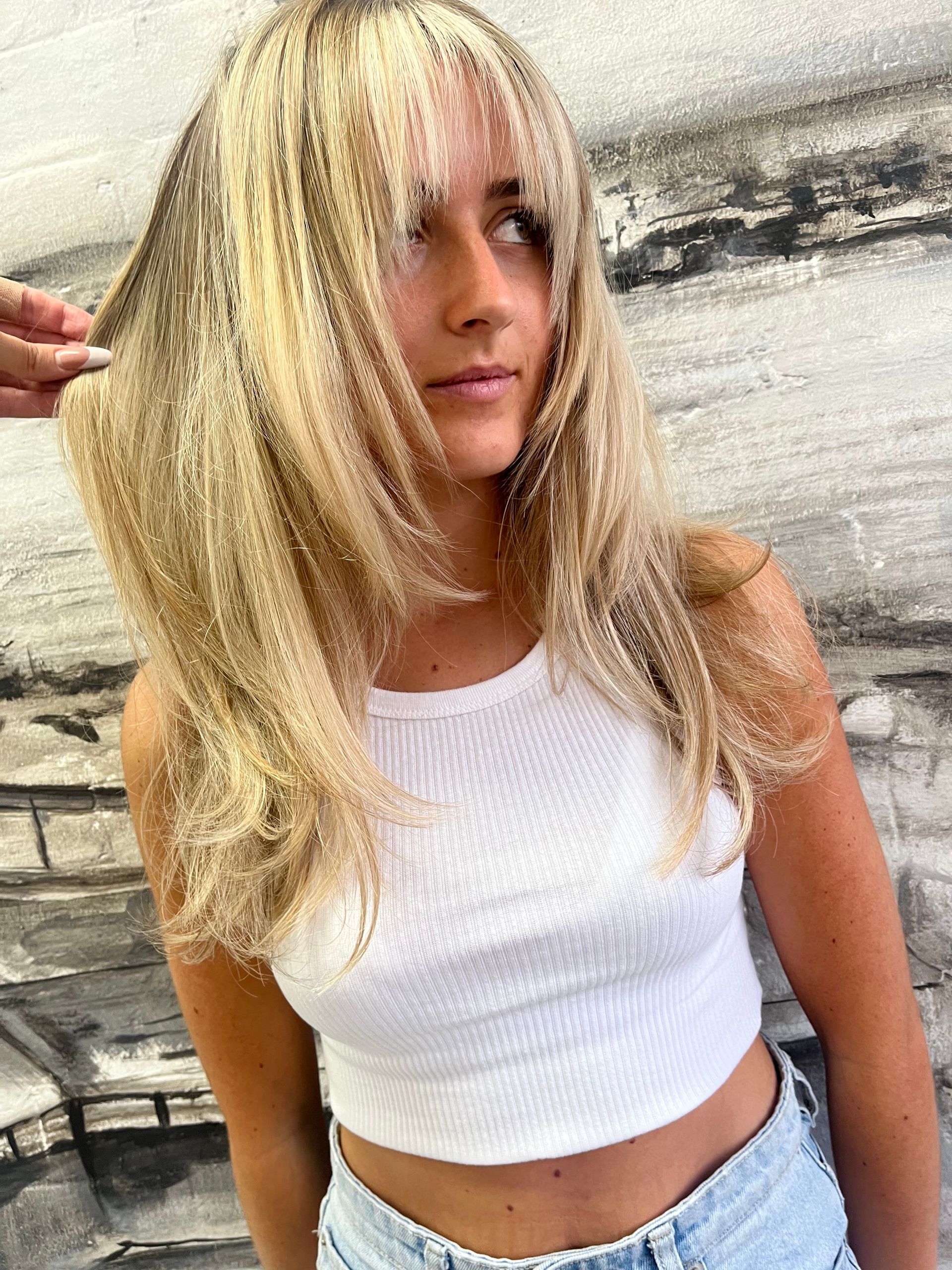 A Woman With Long Blonde Hair Is Getting Her Hair Cut By A Hairdresser — Genesis Hair and Beauty In Port Kembla, NSW 