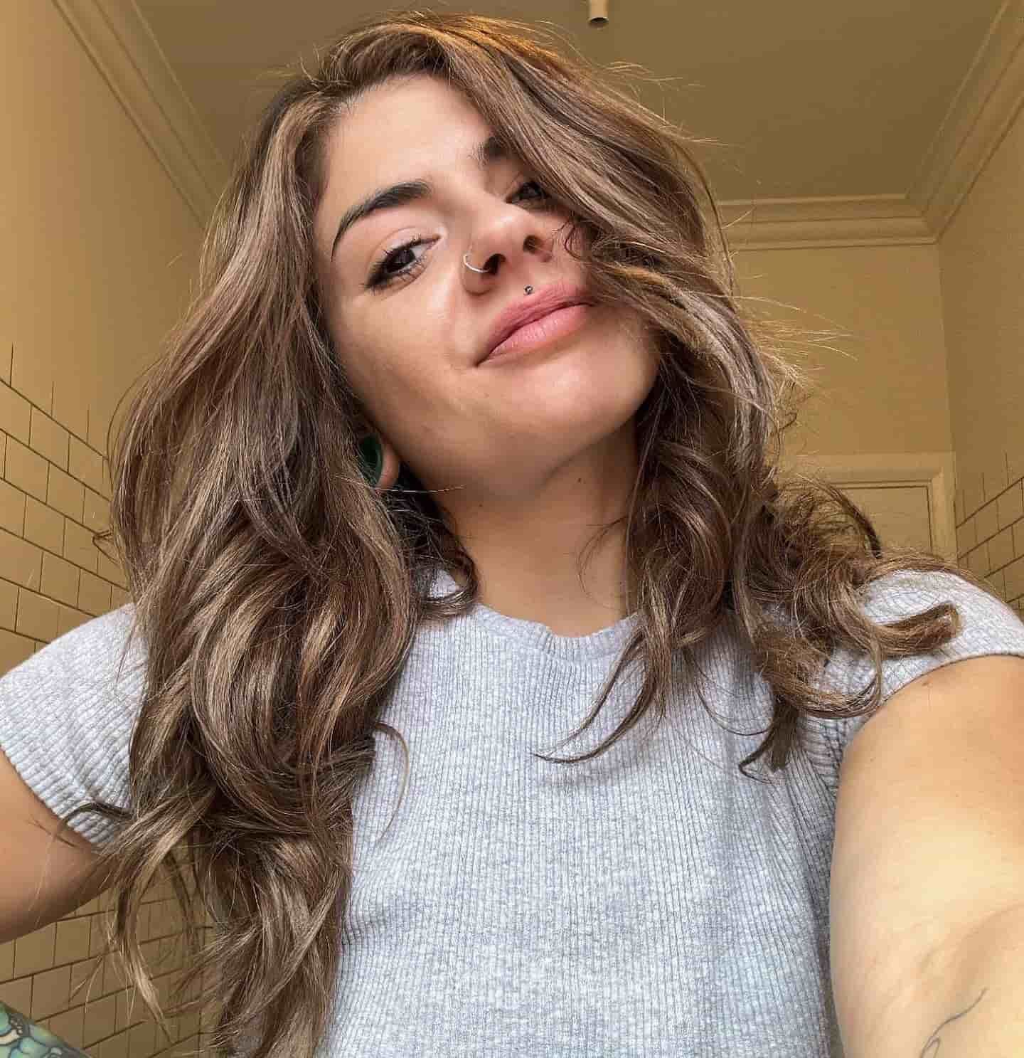A Woman With Long Brown Hair Is Taking A Selfie In A Bathroom — Genesis Hair and Beauty In Port Kembla, NSW 