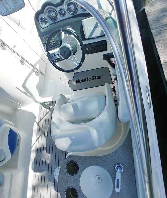 Boat helm with steering wheel, gauges, and white captain’s chair on a NauticStar console