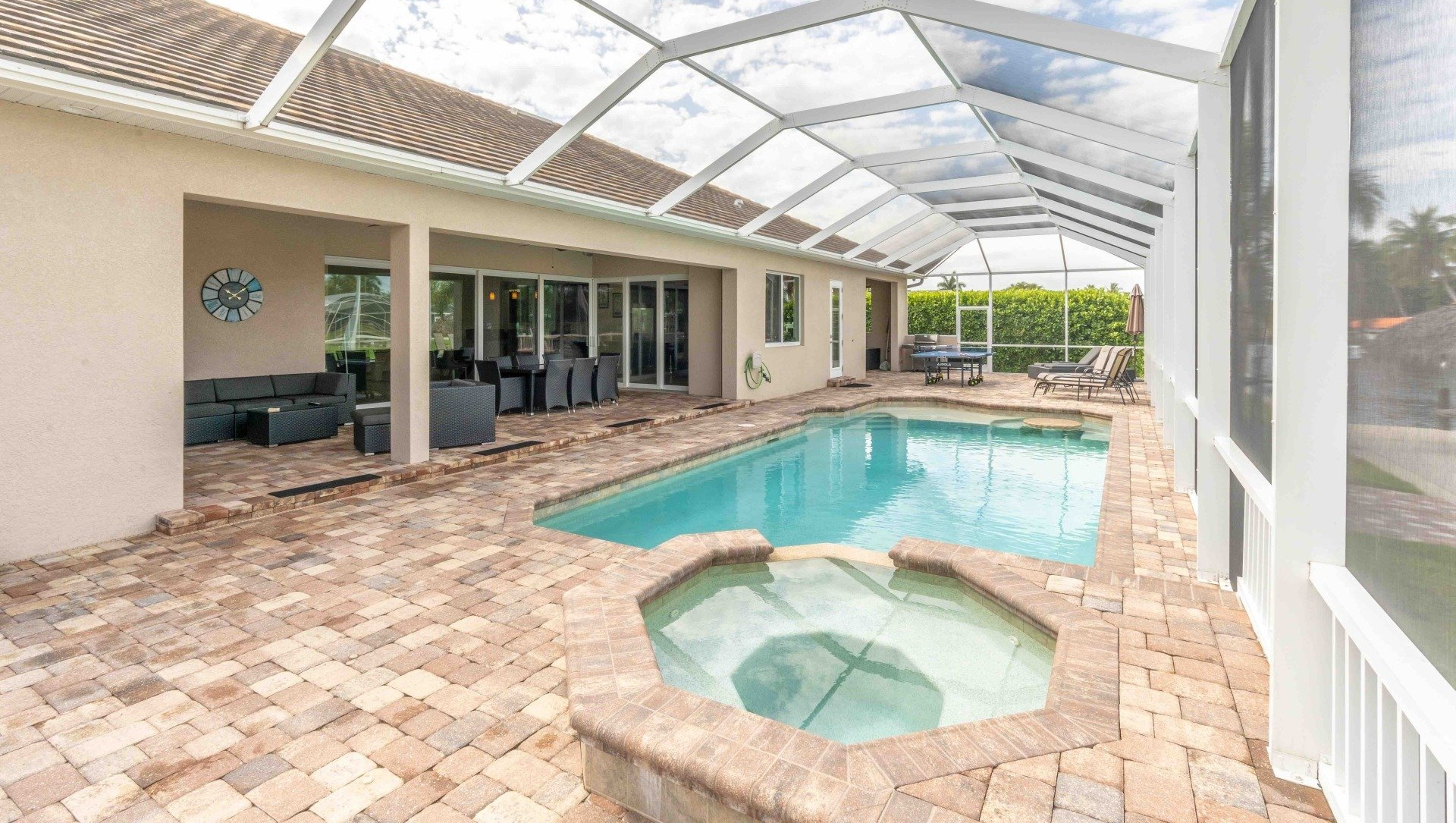 Covered backyard pool with spa, brick patio, lounge area, and screened enclosure
