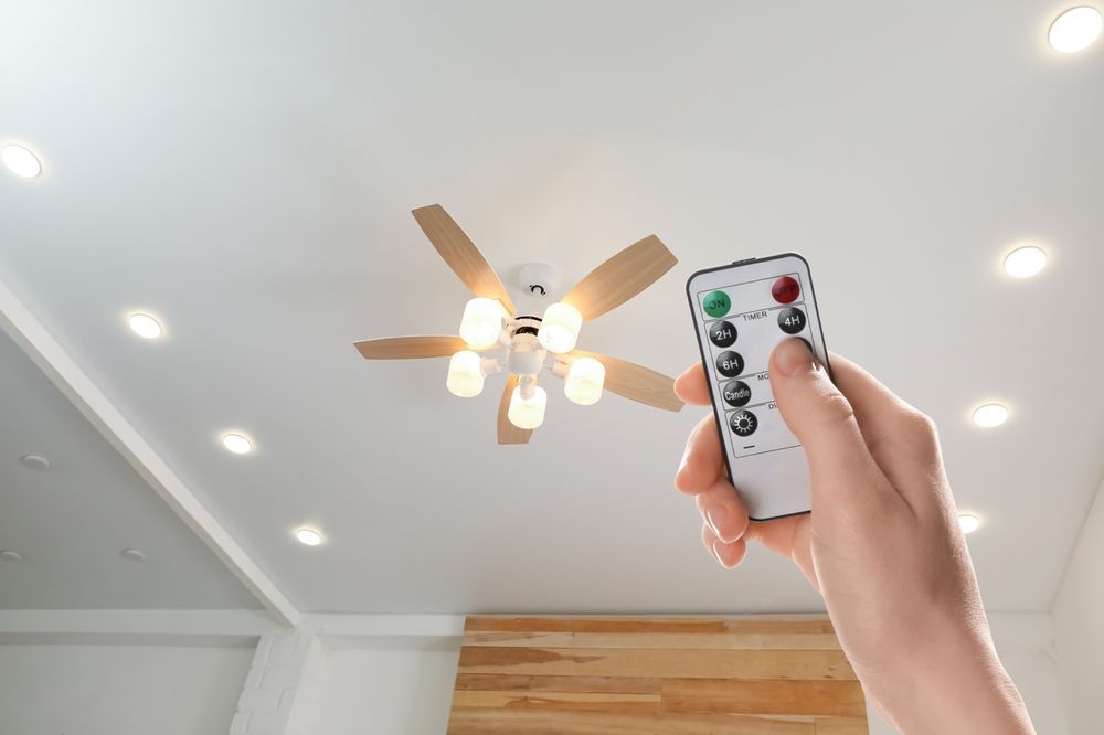 Modern white ceiling with black ceiling fan and track lights, viewed from below by a staircase.
