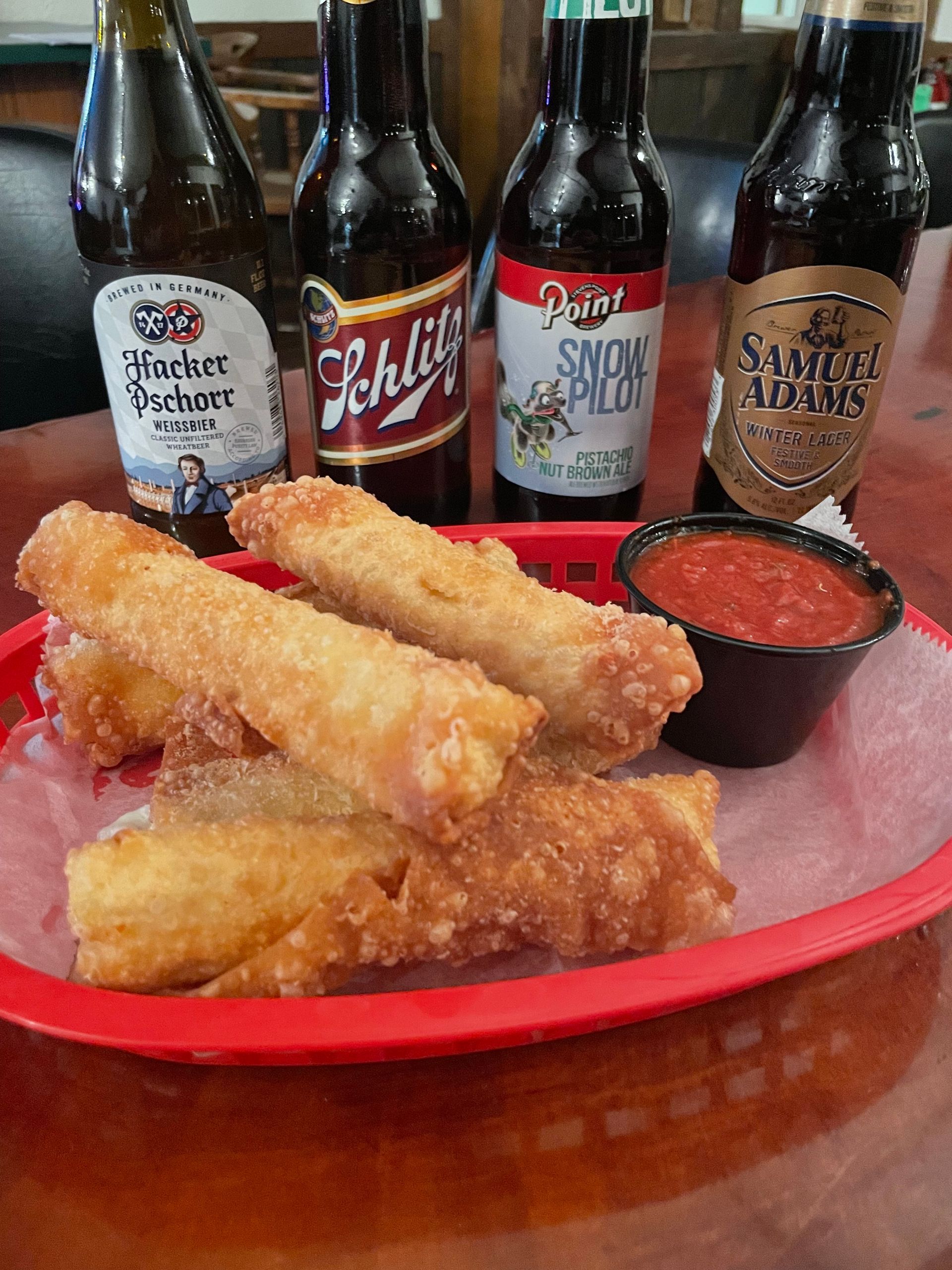 A red basket filled with fried food and bottles of beer on a table.