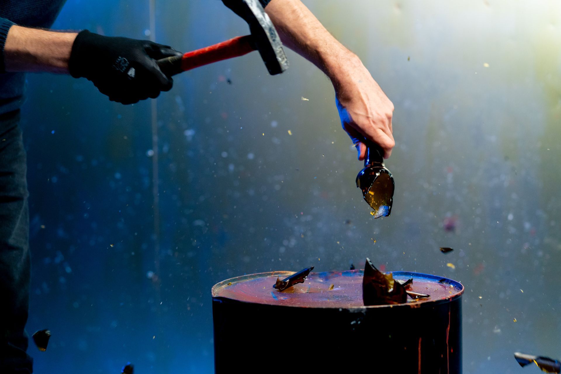 Person with hammer breaking object on a drum, shards of material flying.