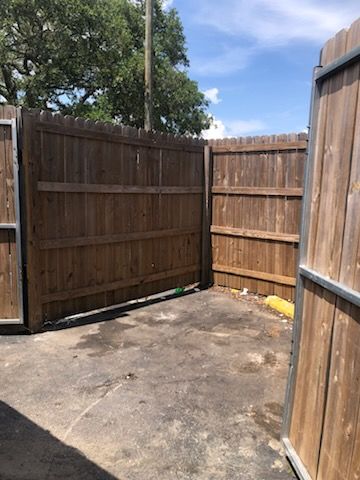 Wooden fenced corner with a concrete patio under a blue sky
