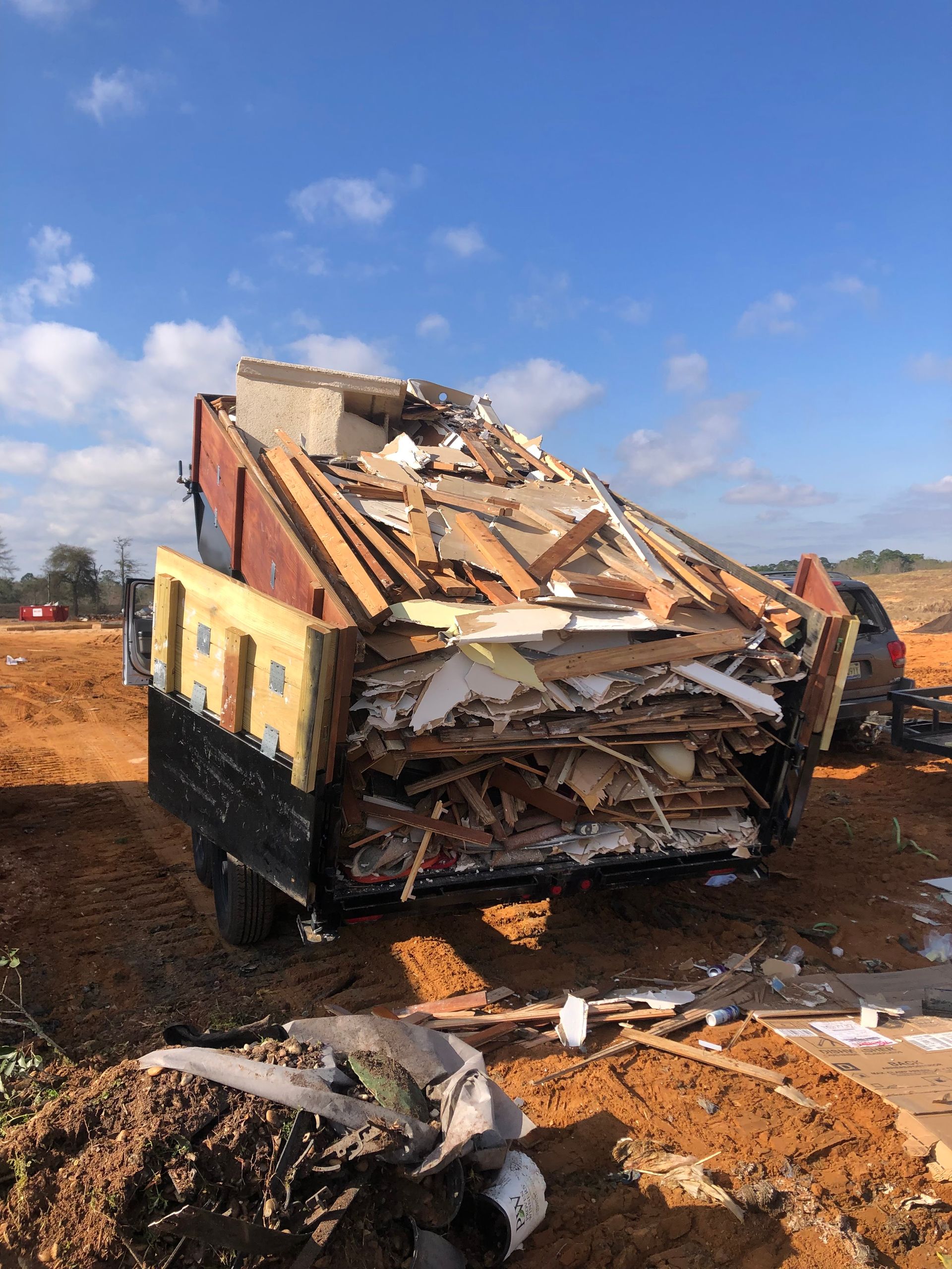 Damaged truck wreckage on a dirt lot under a blue sky, with debris scattered in front
