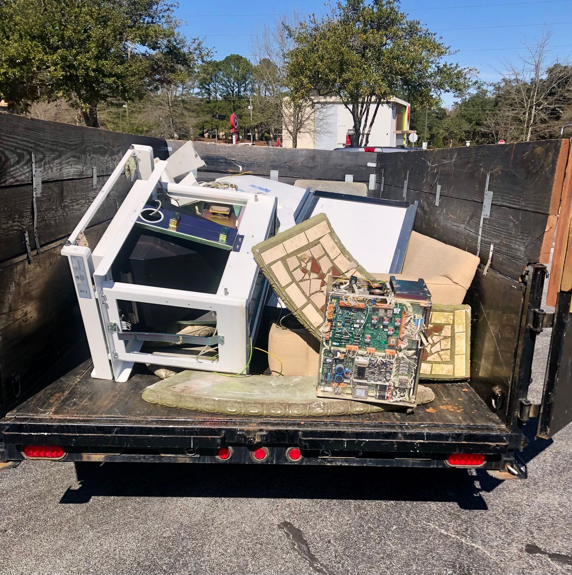 Damaged furniture and debris piled in a trailer at a roadside cleanup site