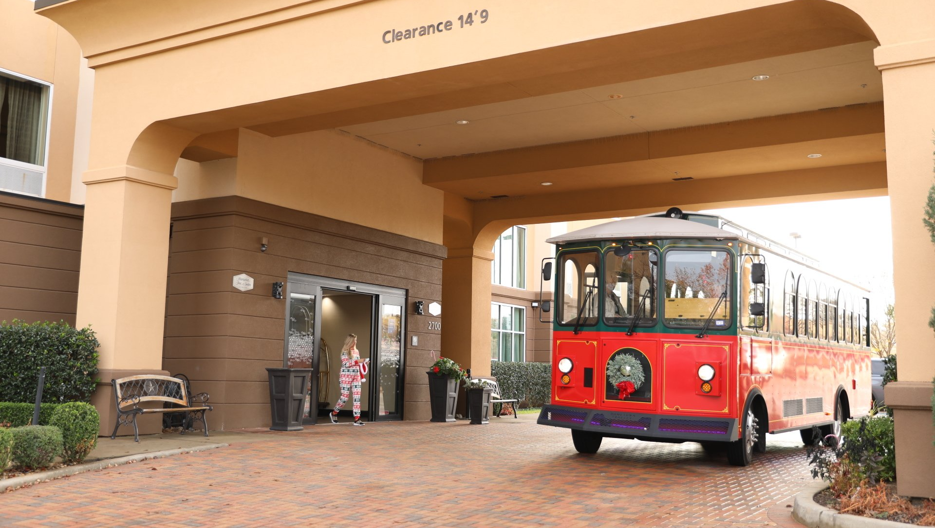 Red trolley in front of a hotel entrance; a woman exits the building.