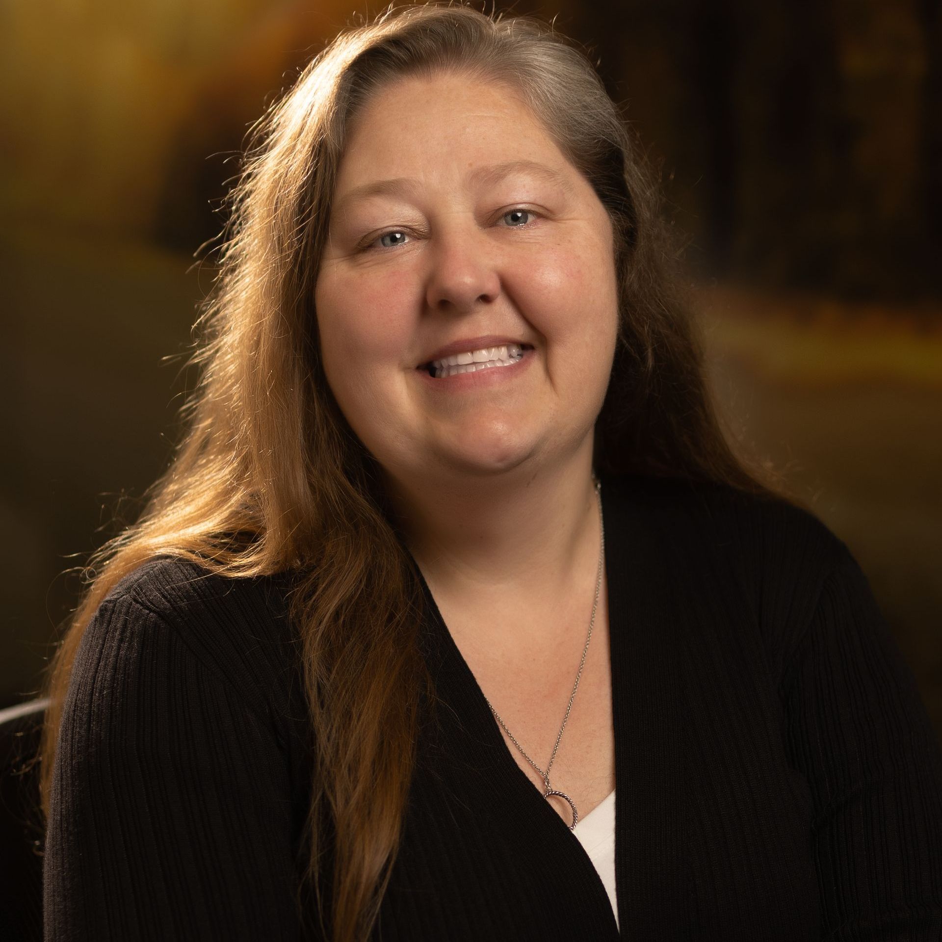 A woman in a black sweater is smiling for the camera.