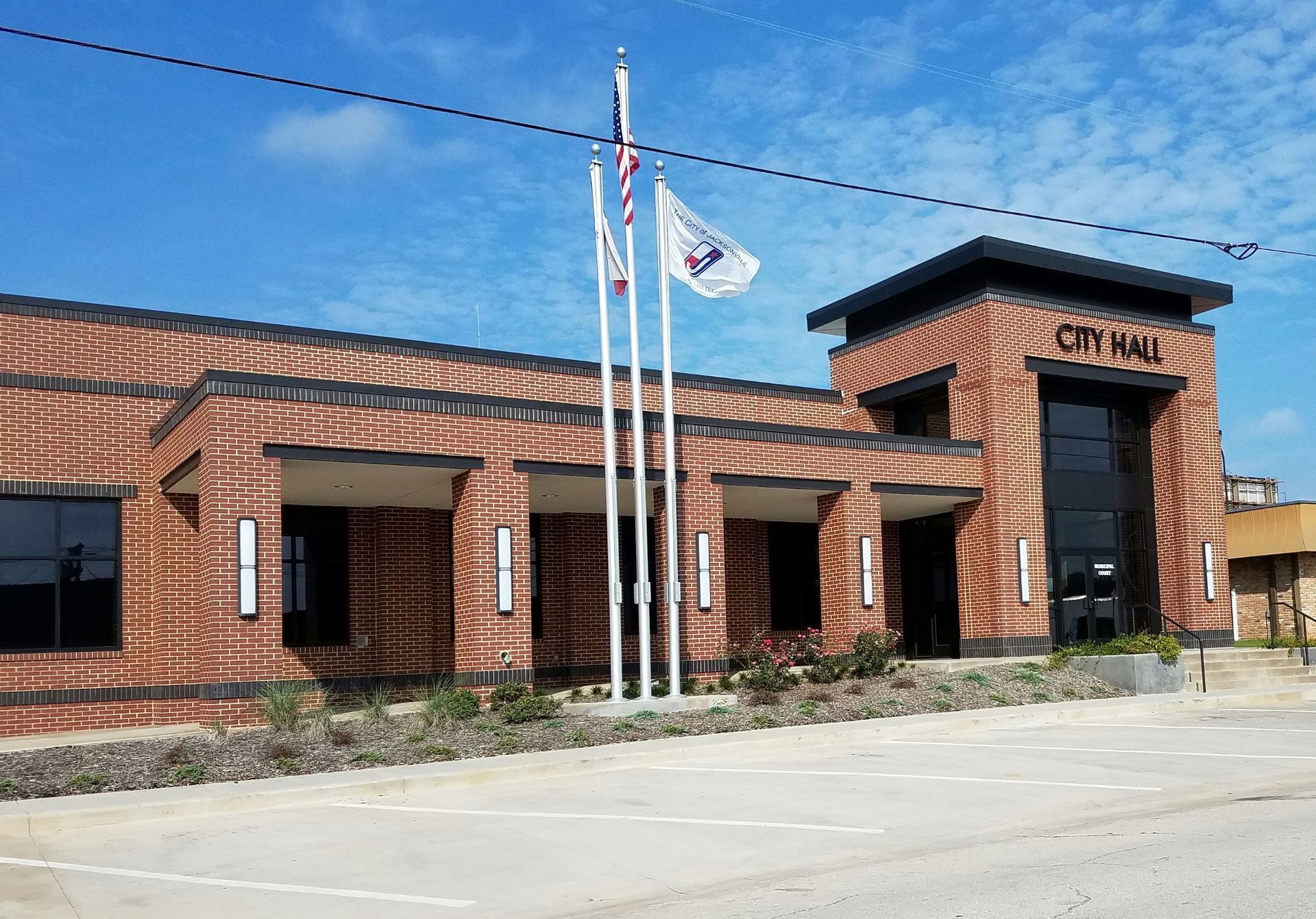 A large brick building with three flags flying in front of it.